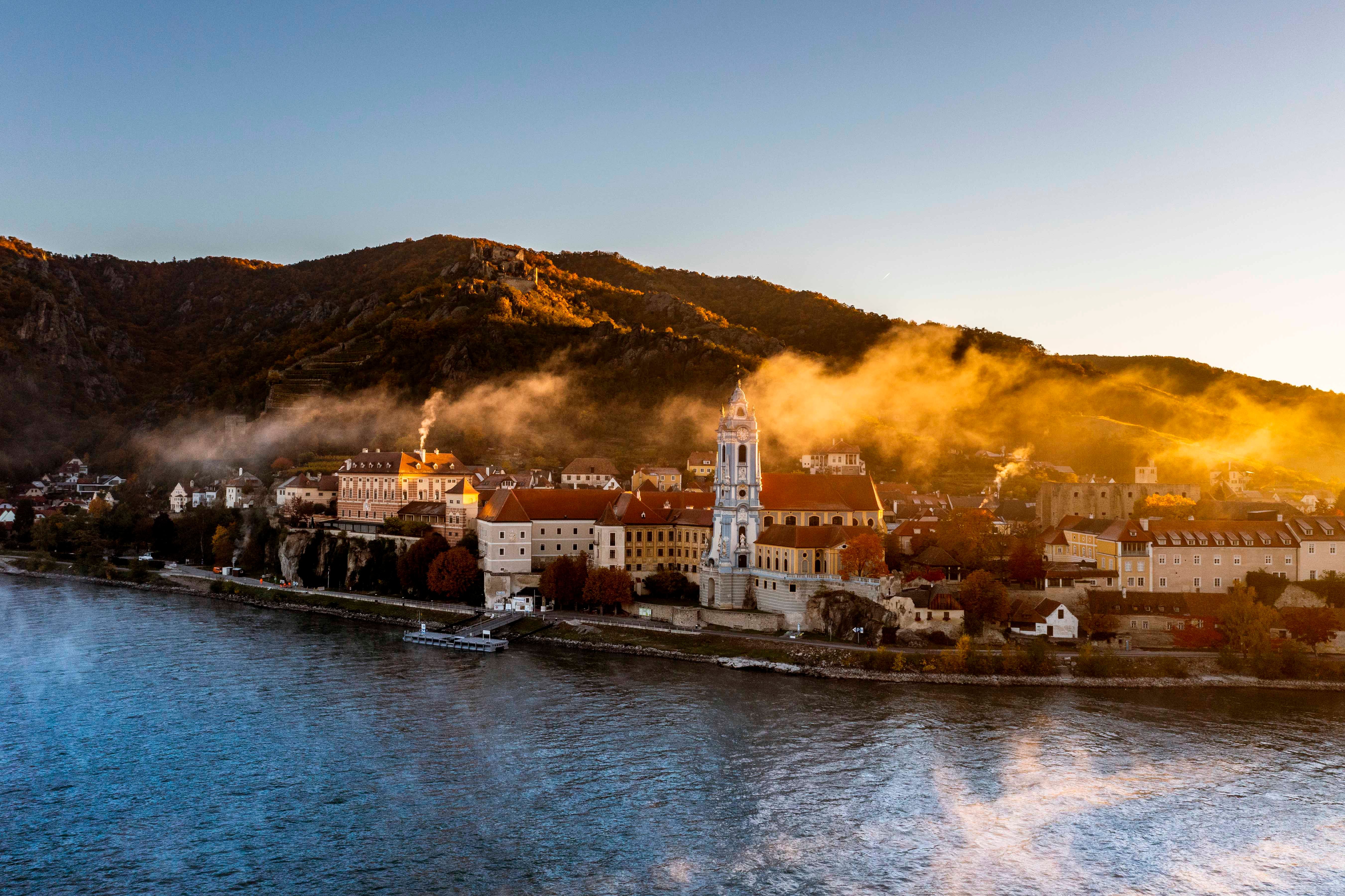Außenansicht von Dürnstein mit Schloss und Kirche am Flussufer.