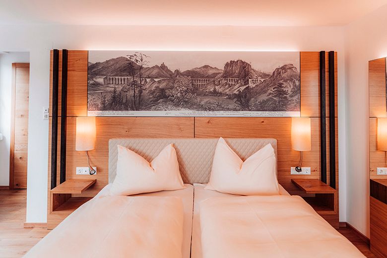 Ein modernes Doppelzimmer mit zwei Betten, Holzmöbeln und einem Landschaftsbild über dem Bett.