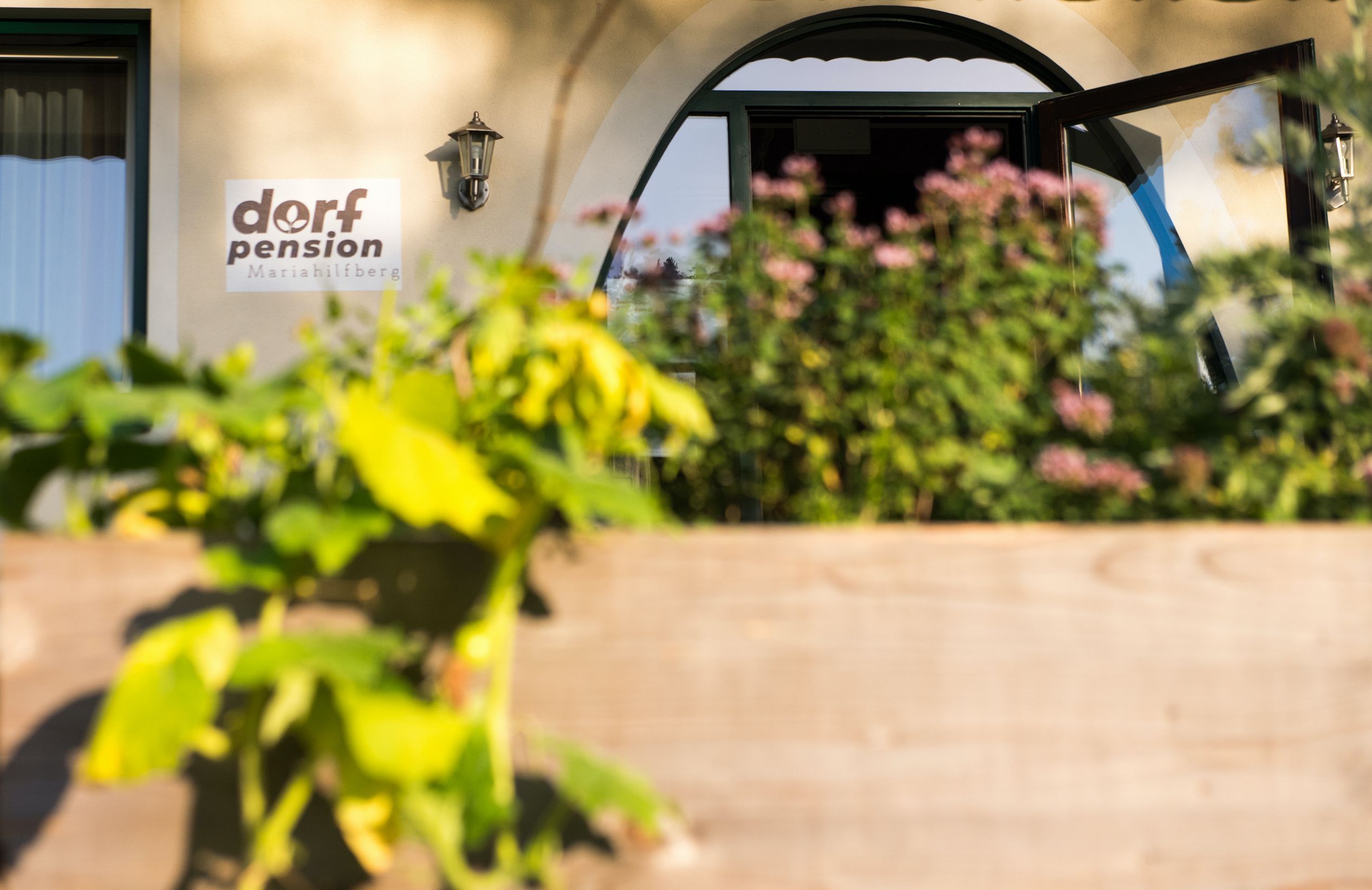 Eingang der Dorfpension Mariahilfberg mit Pflanzen im Vordergrund.