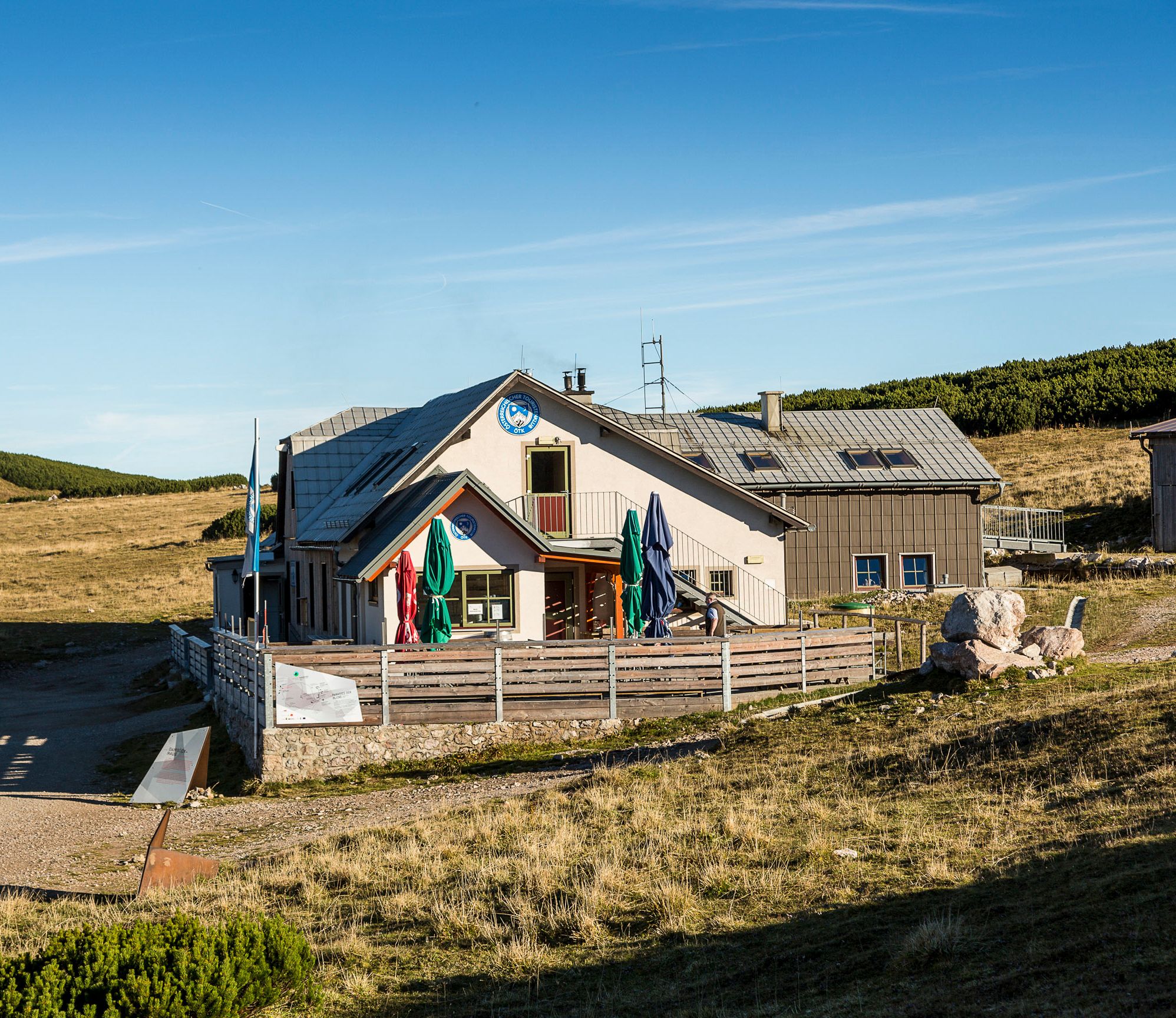 Das Damböckhaus am Schneeberg in einer sonnigen Berglandschaft mit blauem Himmel.