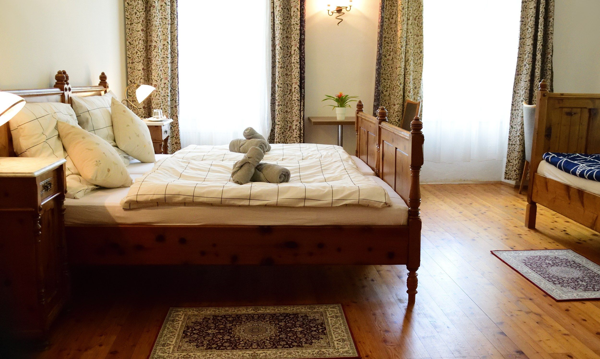 Gemütliches Schlafzimmer mit Holzbett, Nachttischen und dekorativen Handtüchern auf dem Bett.