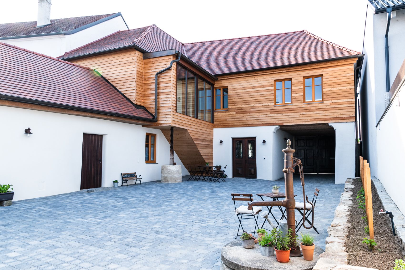 Innenhof eines Gästehauses mit Holzelementen und gepflastertem Boden.