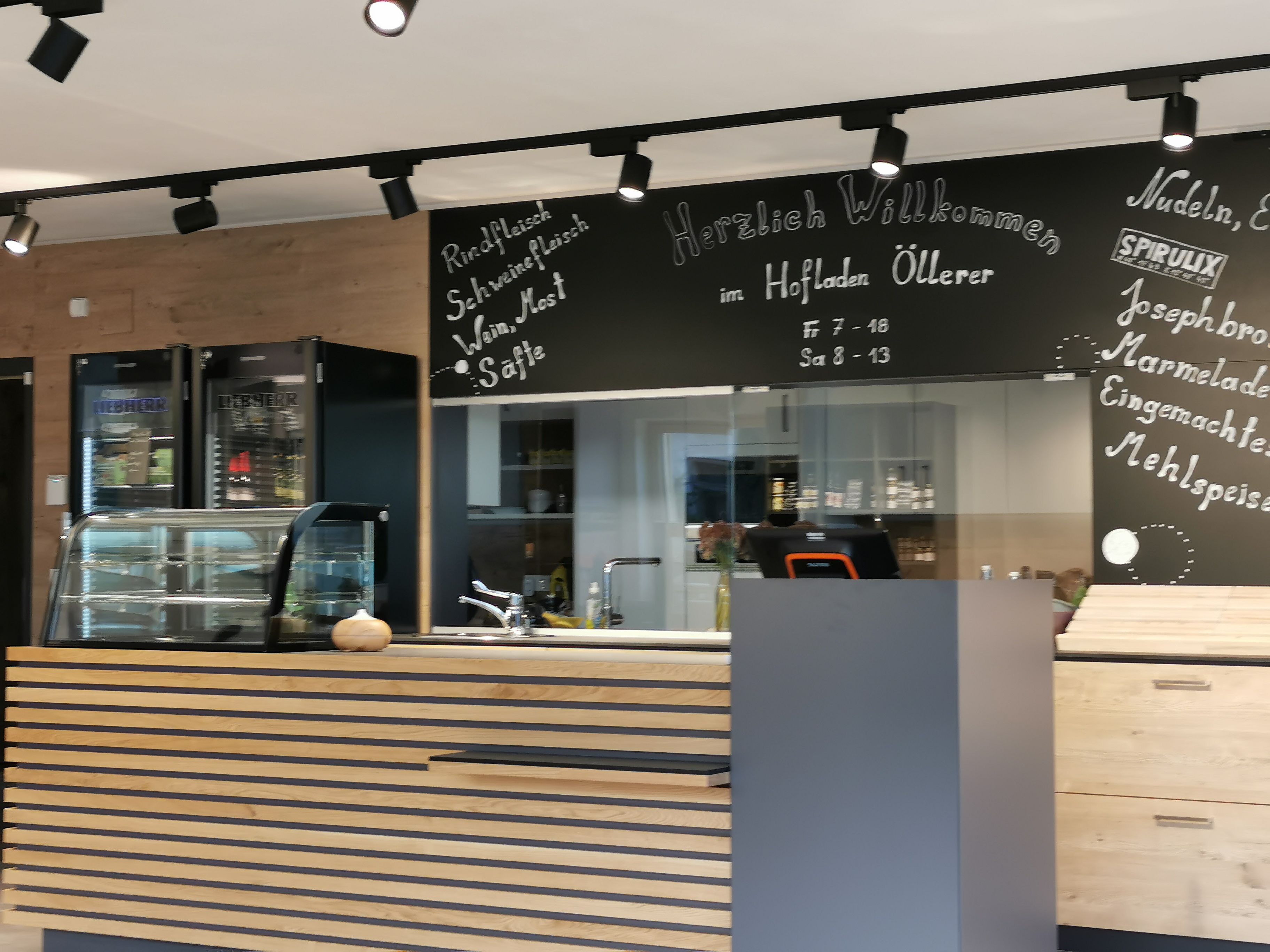 Detailansicht vom Hofladen. Theke und dahinter steht das Angebot auf einer Kreidetafel.