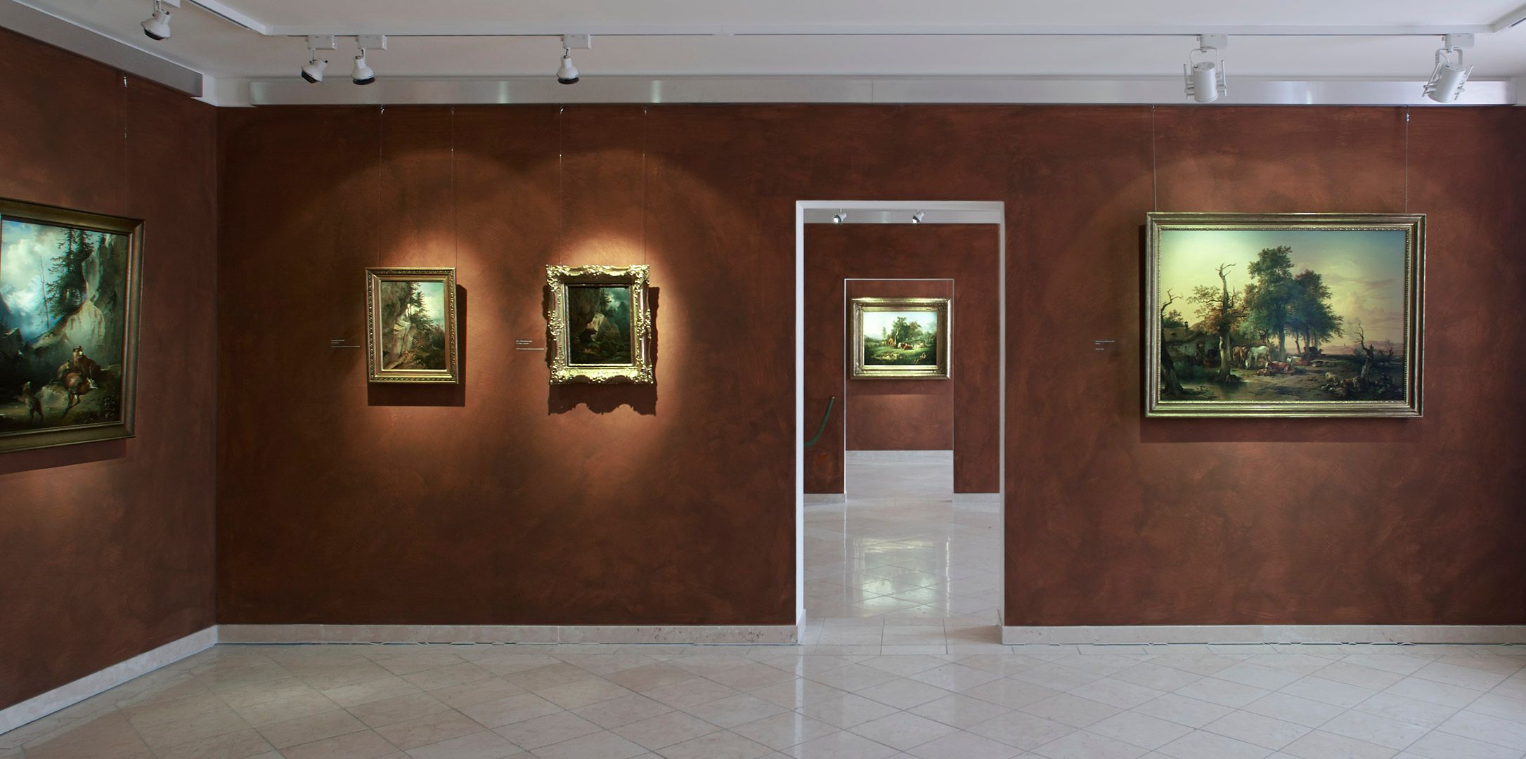 Innenansicht eines Museums mit Gemälden an braunen Wänden.