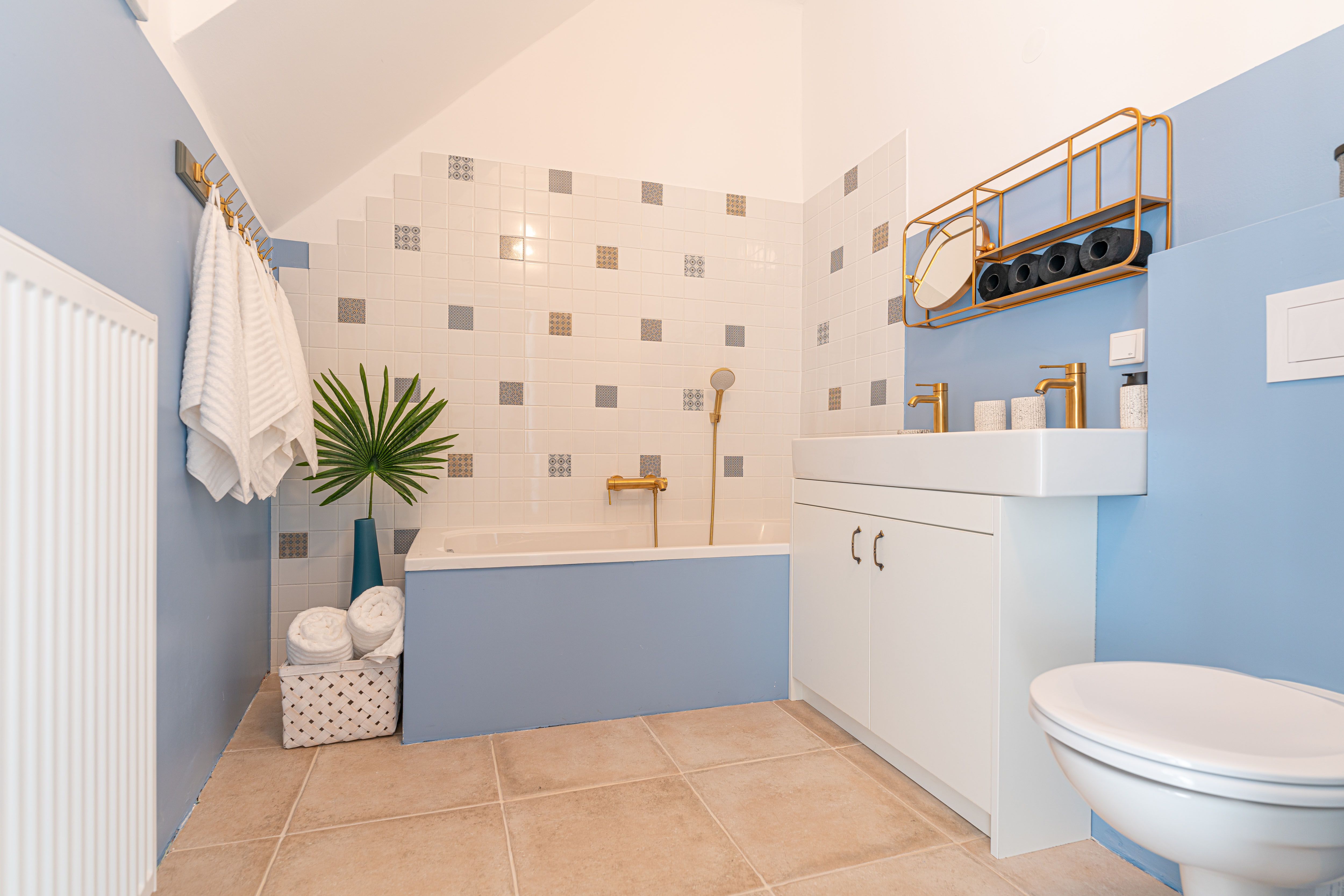 Modernes Badezimmer mit blauen Wänden, Badewanne, Waschbecken und goldenen Armaturen.