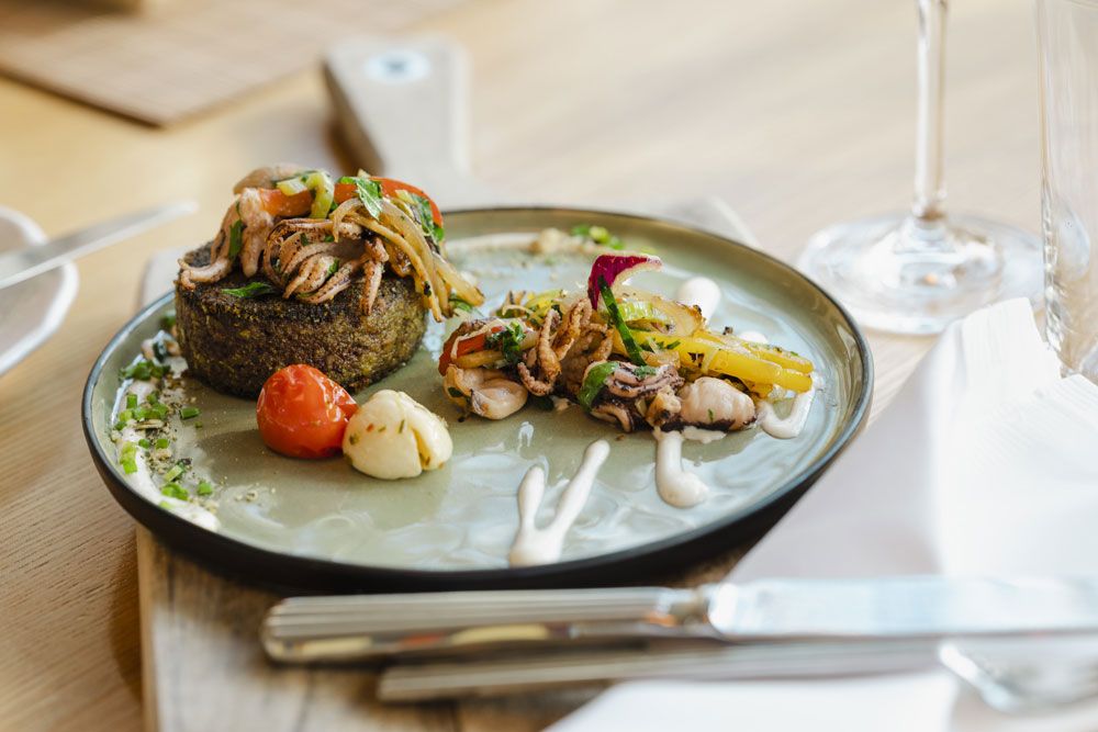 Gourmetgericht auf einem Teller mit Gemüse und Meeresfrüchten, dekorativ angerichtet.