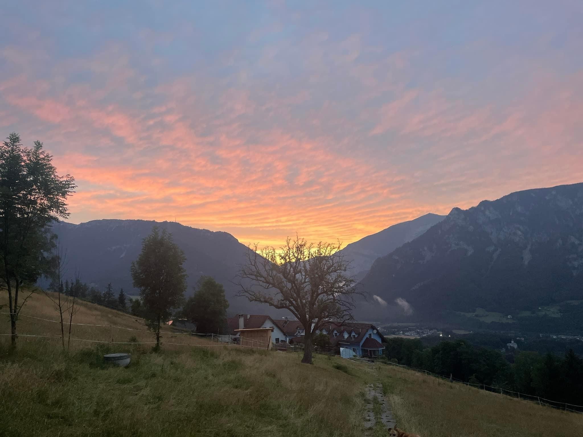 Blick auf ein Haus in einer Berglandschaft bei Sonnenuntergang.