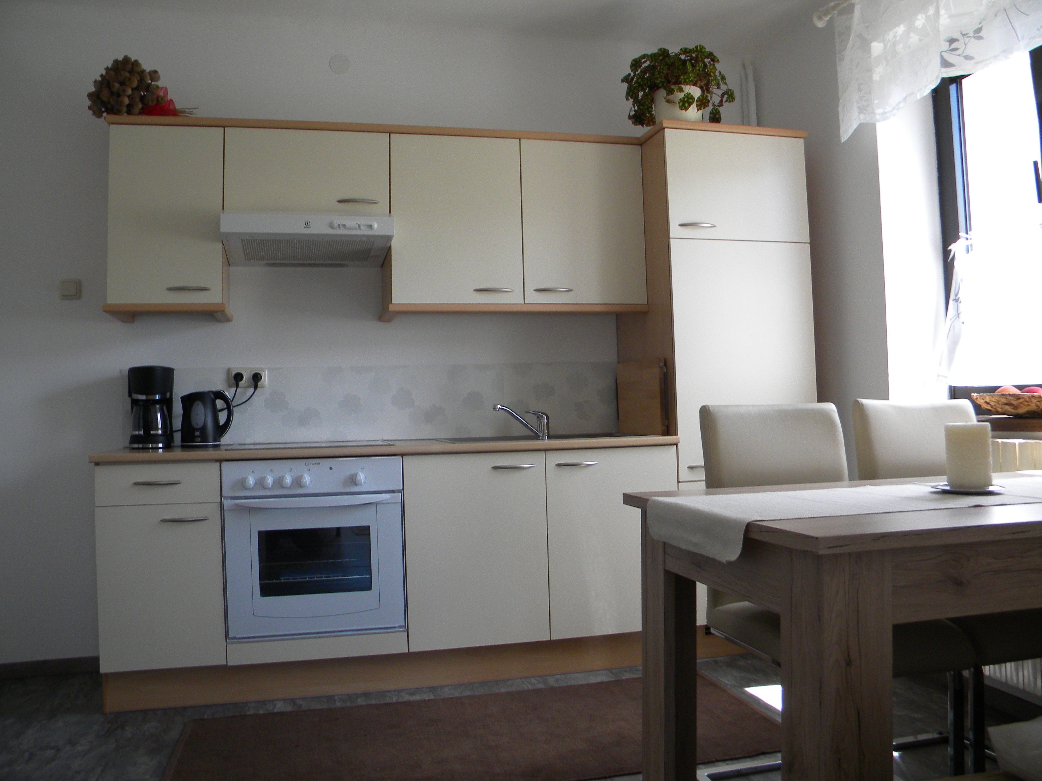 Moderne Küche mit cremefarbenen Schränken, Esstisch und Stühlen.