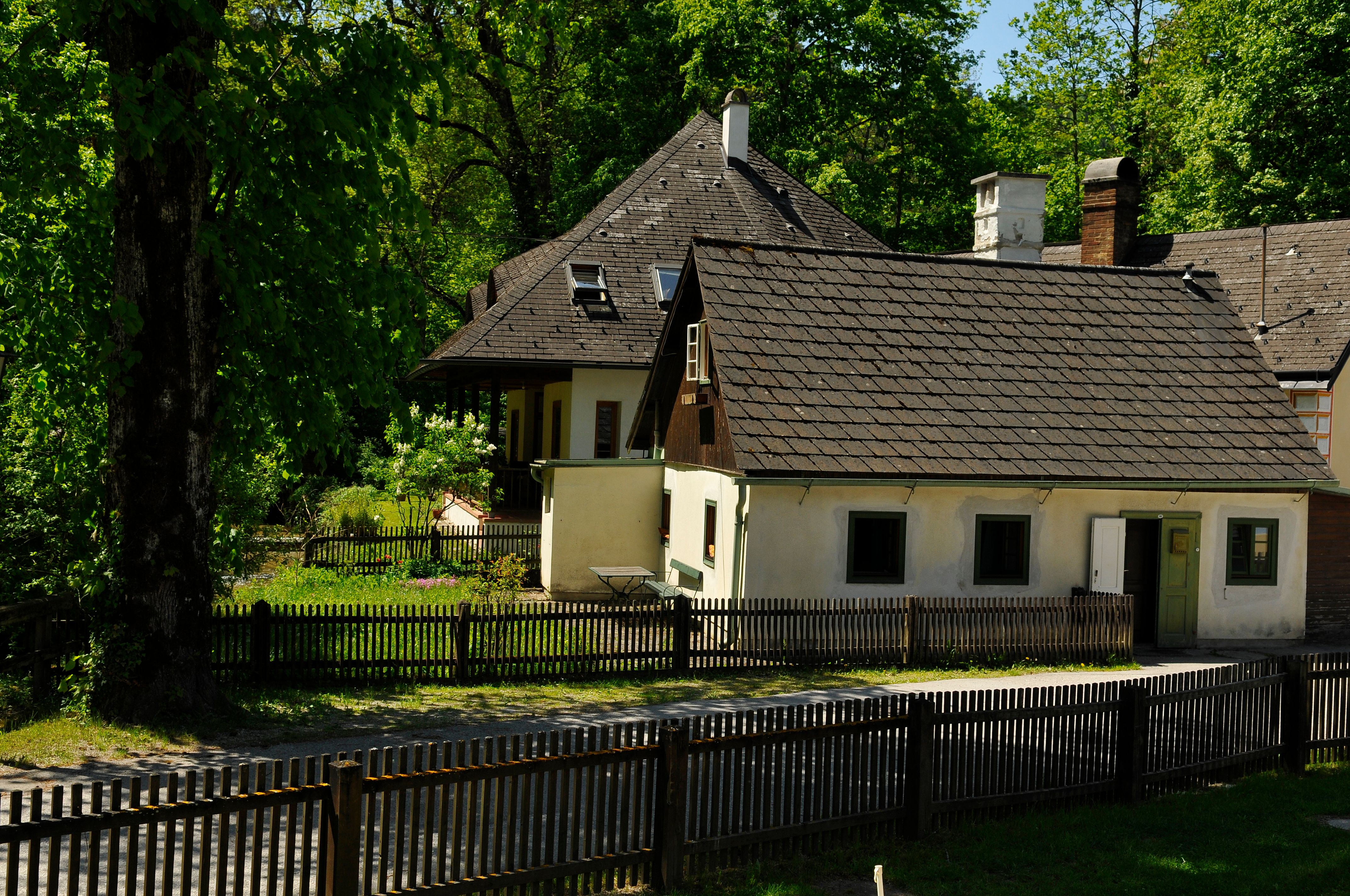 Ein traditionelles Gästehaus mit Holzzaun und Garten, umgeben von Bäumen.