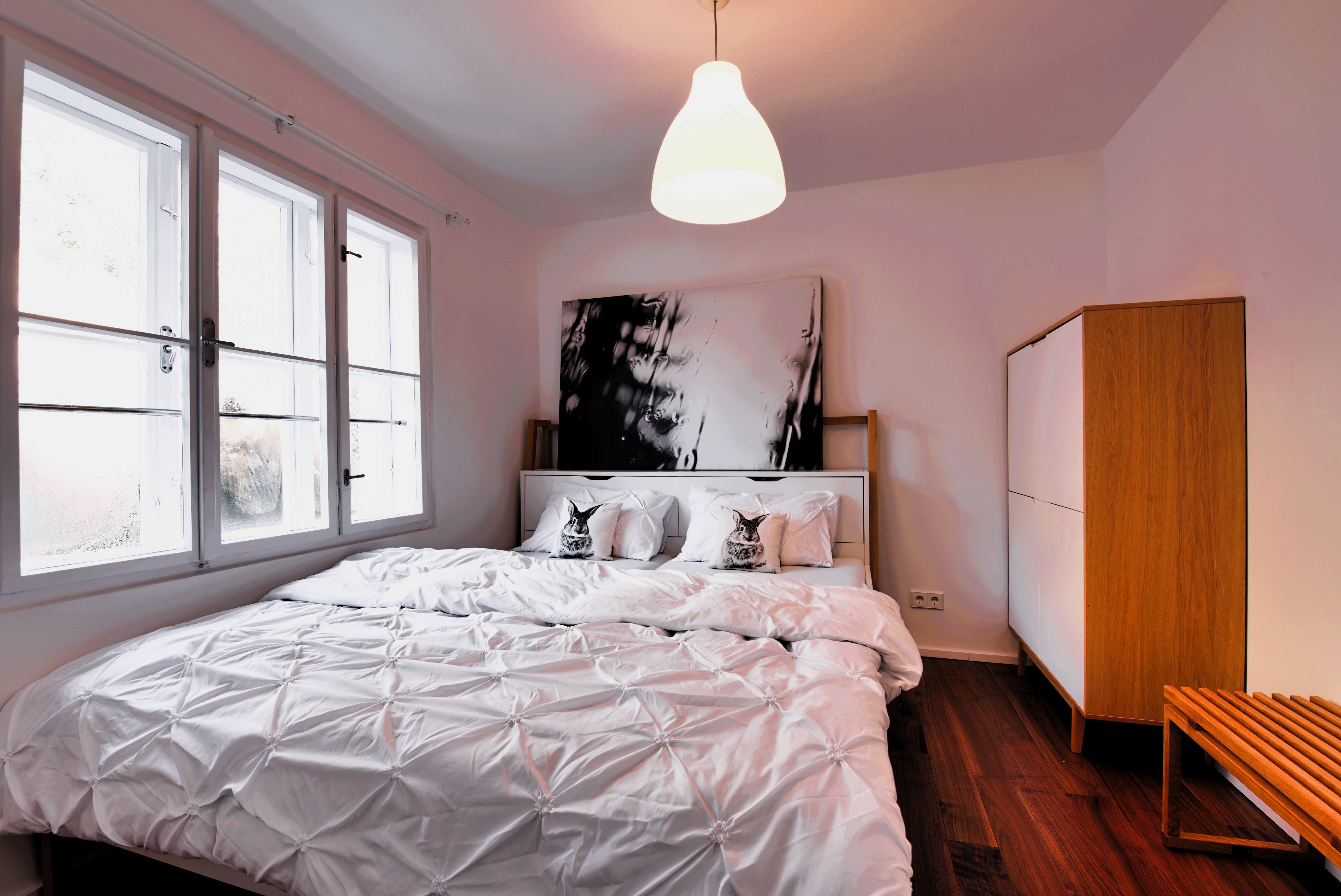 Modernes Schlafzimmer mit großem Bett, weißer Bettwäsche und Holzschrank.