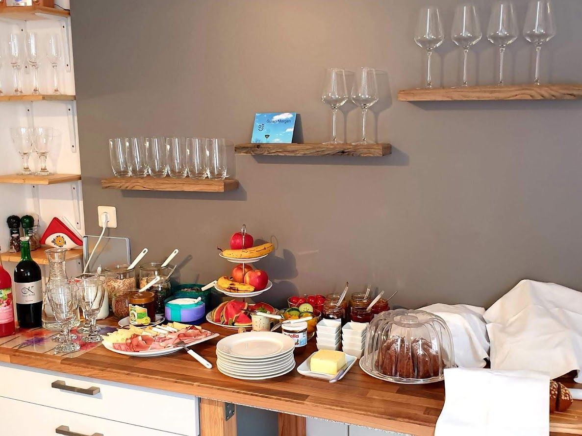 Frühstücksbuffet mit Gläsern, Obst, Aufschnitt und Kuchen.