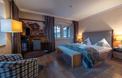 Hotelzimmer mit Doppelbett, Sessel, Tisch und Fenster mit Ausblick.