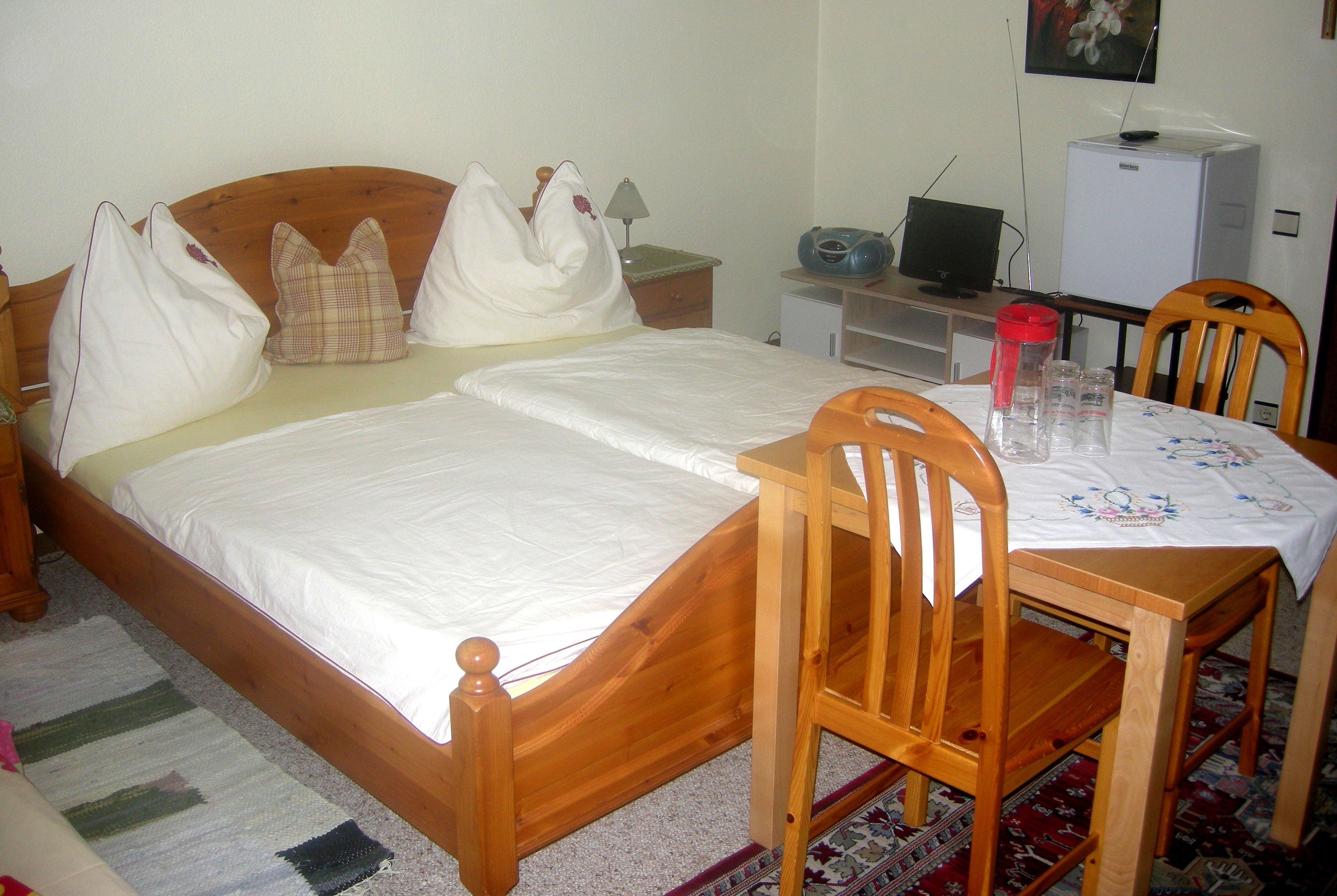 Ein gemütliches Schlafzimmer mit Holzmöbeln, einem Doppelbett, einem kleinen Tisch mit Stühlen und einem Fernseher.