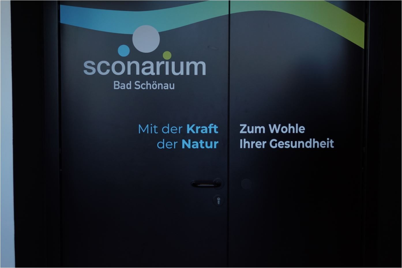 Tür mit dem Logo von Sconarium Bad Schönau und dem Slogan 'Mit der Kraft der Natur, Zum Wohle Ihrer Gesundheit'.