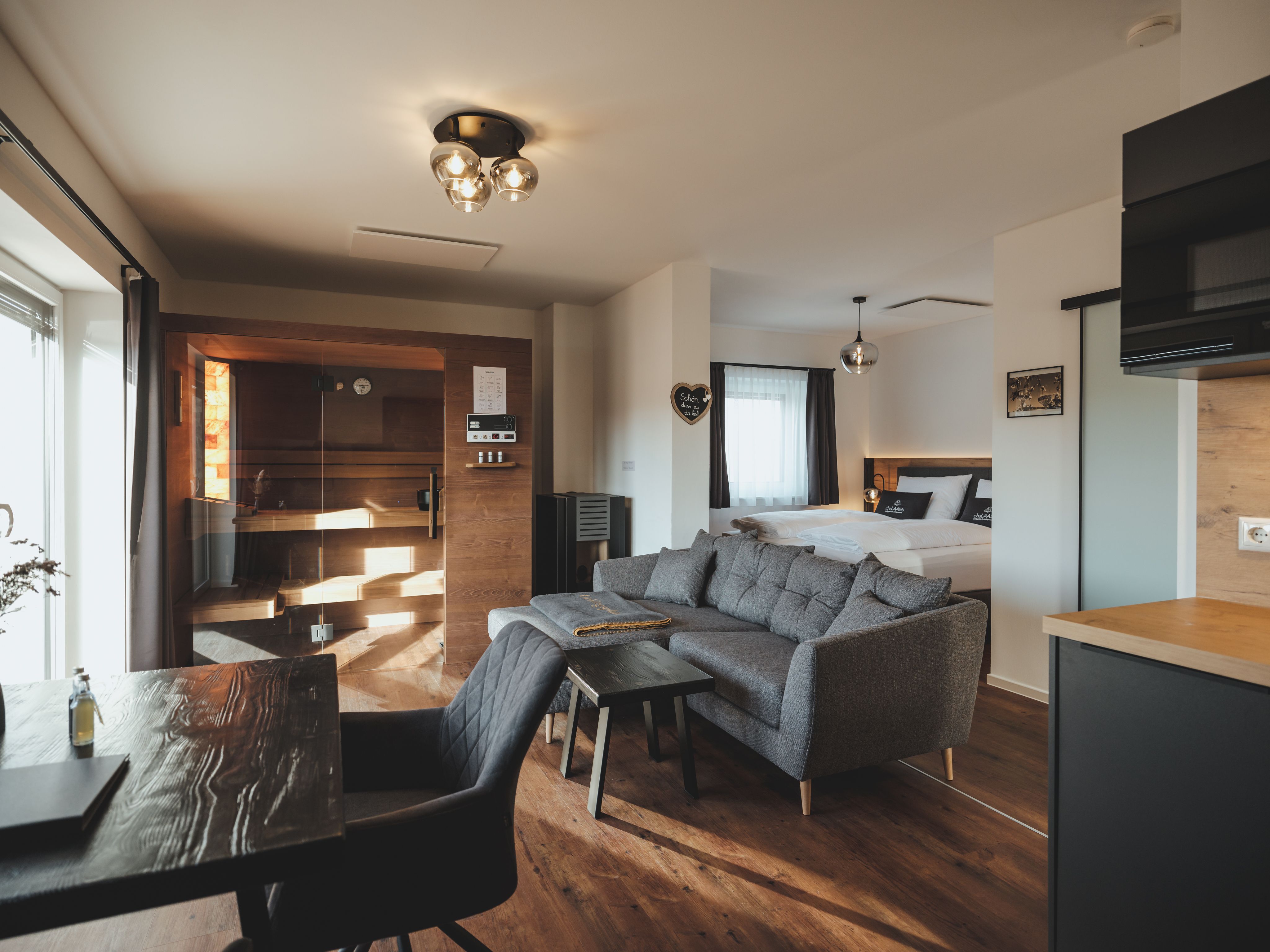 Innenansicht eines Chalets mit Sauna, Sofa und Bett.