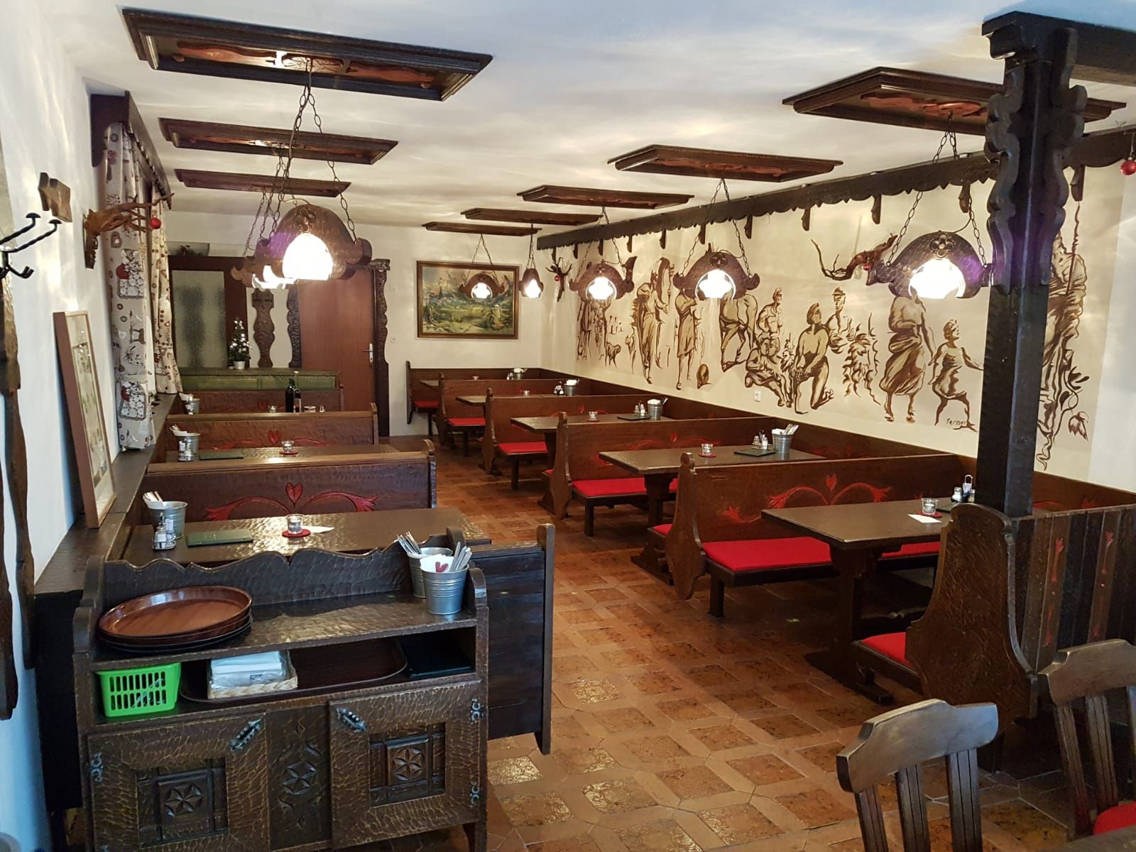 Innenansicht einer traditionellen Buschenschank mit Holzmöbeln und Wandmalereien.