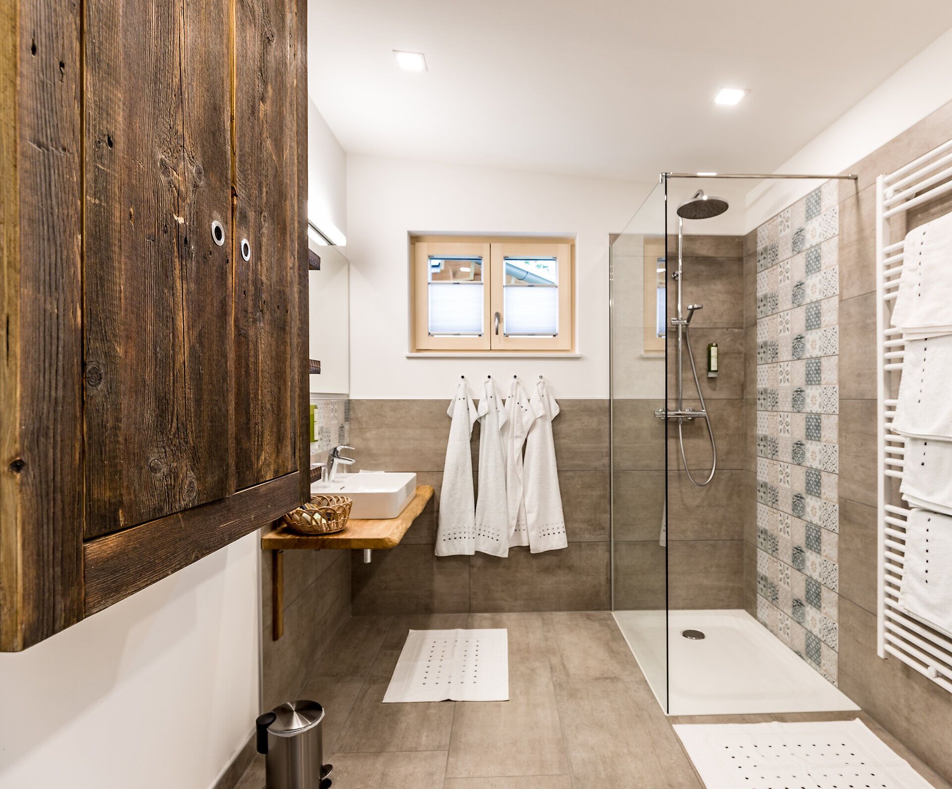 In einem stilvollen Badezimmer vereinen sich moderne Eleganz und natürliche Materialien. Die großzügige Dusche und die sanften Erdtöne schaffen eine entspannende Atmosphäre, die zum Verweilen einlädt. Hier findet man den perfekten Rückzugsort nach einem erlebnisreichen Tag in der Natur.