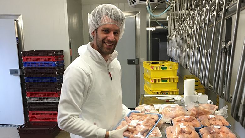 Ein Mann in Schutzkleidung verpackt Fleisch in einem Verarbeitungsraum.