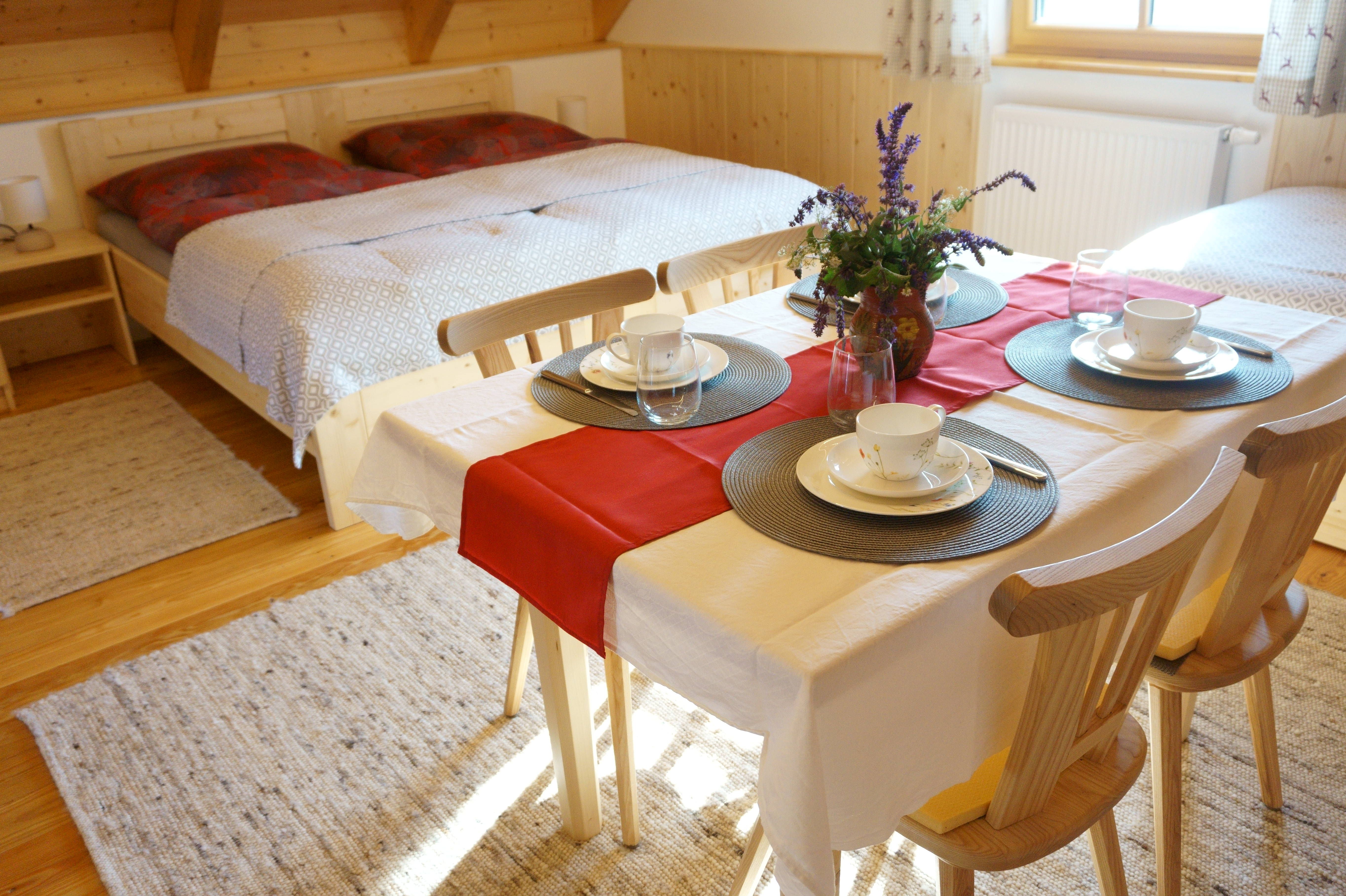 Gemütliches Zimmer mit Doppelbett und Esstisch, gedeckt für vier Personen.