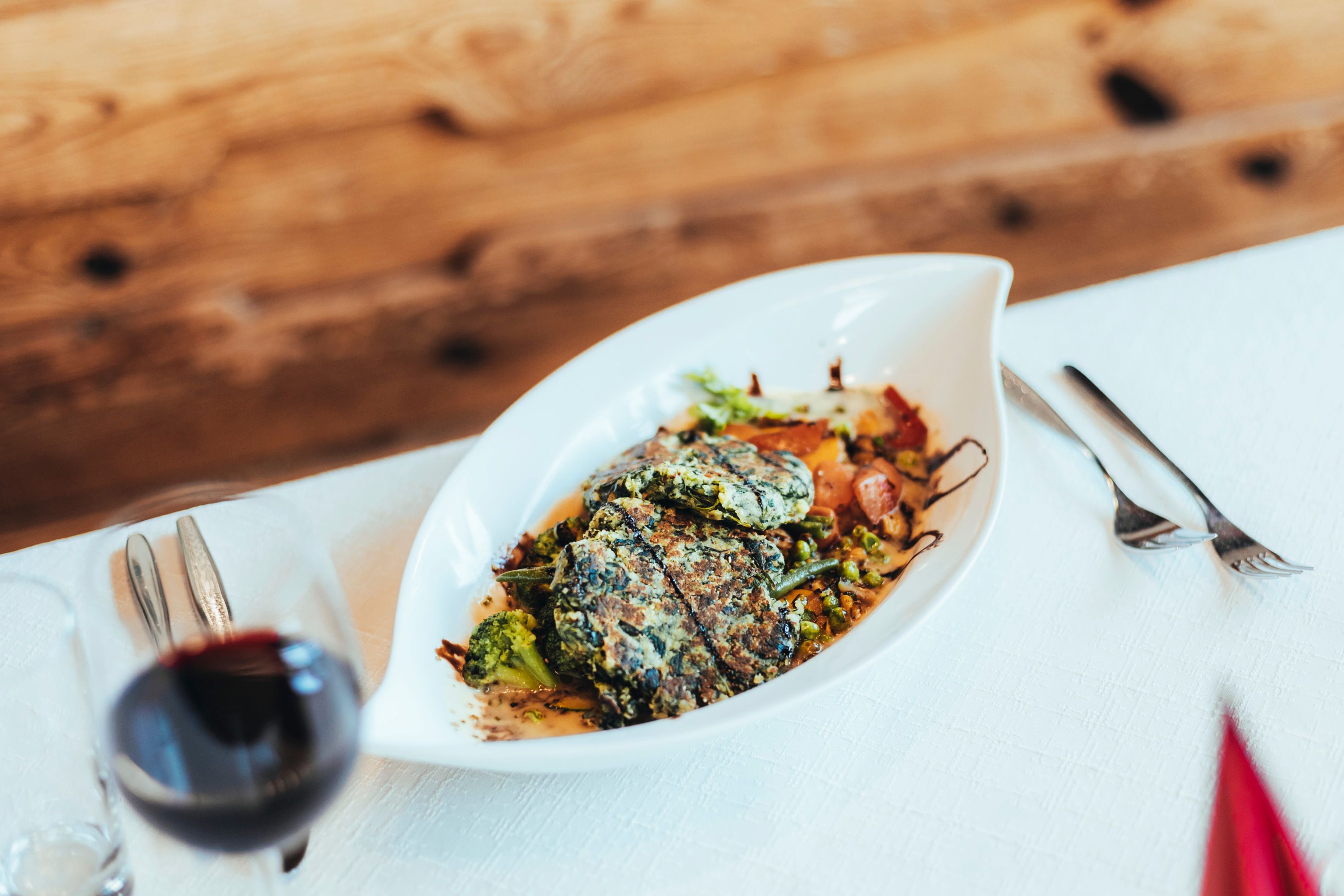 Ein Teller mit Spinat Laibchen und Gemüse auf einem Tisch.