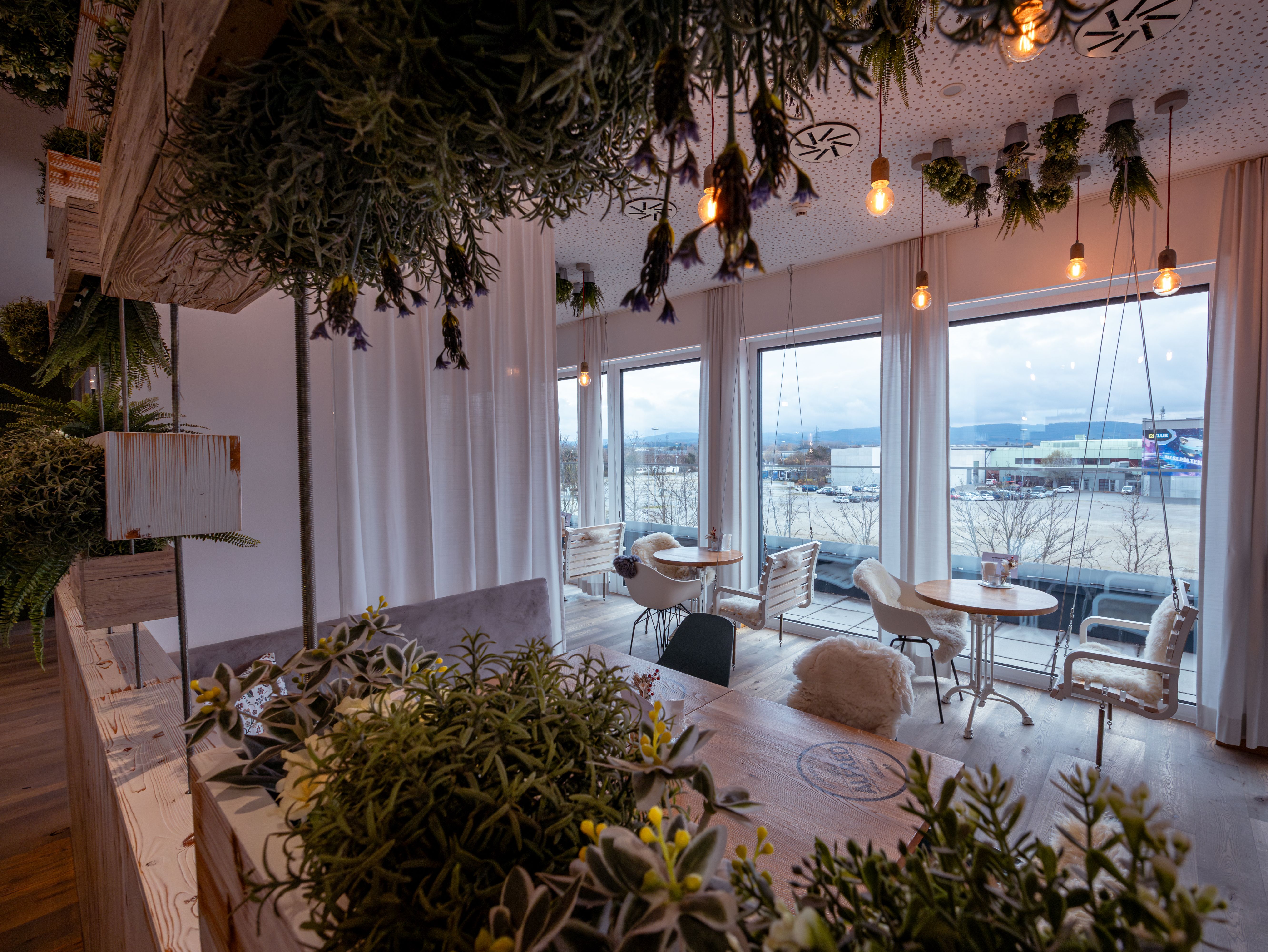 Modernes Hotelzimmer mit Doppelbett, Holzverkleidung und Fenster mit Vorhängen.