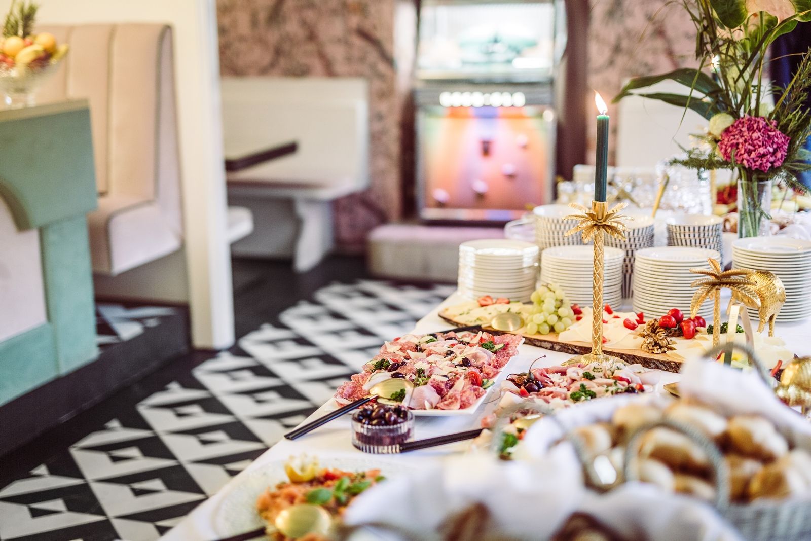 Ein reichhaltiges Buffet mit verschiedenen Speisen, Geschirrstapeln und dekorativen Kerzenhaltern in einem stilvollen Raum.
