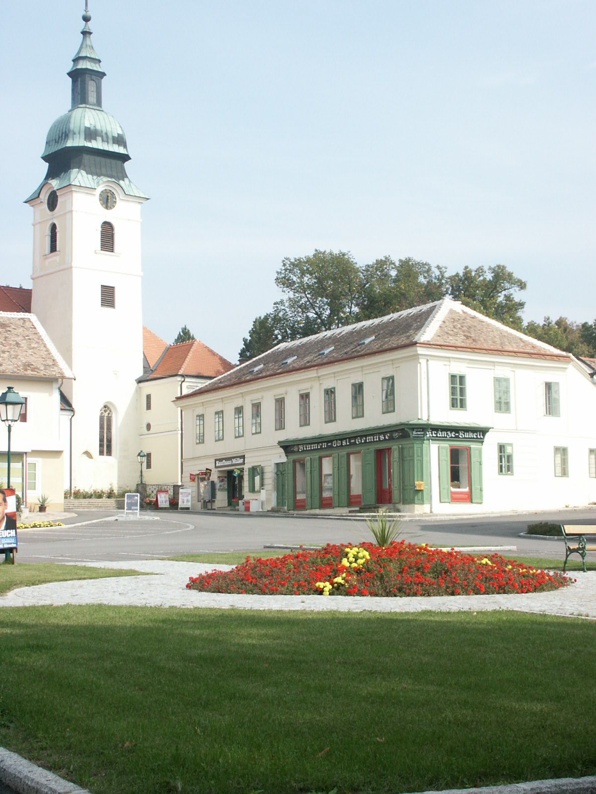 Hauptplatz in Sitzendorf an der Schmida mit Kirche und Blumenbeet.