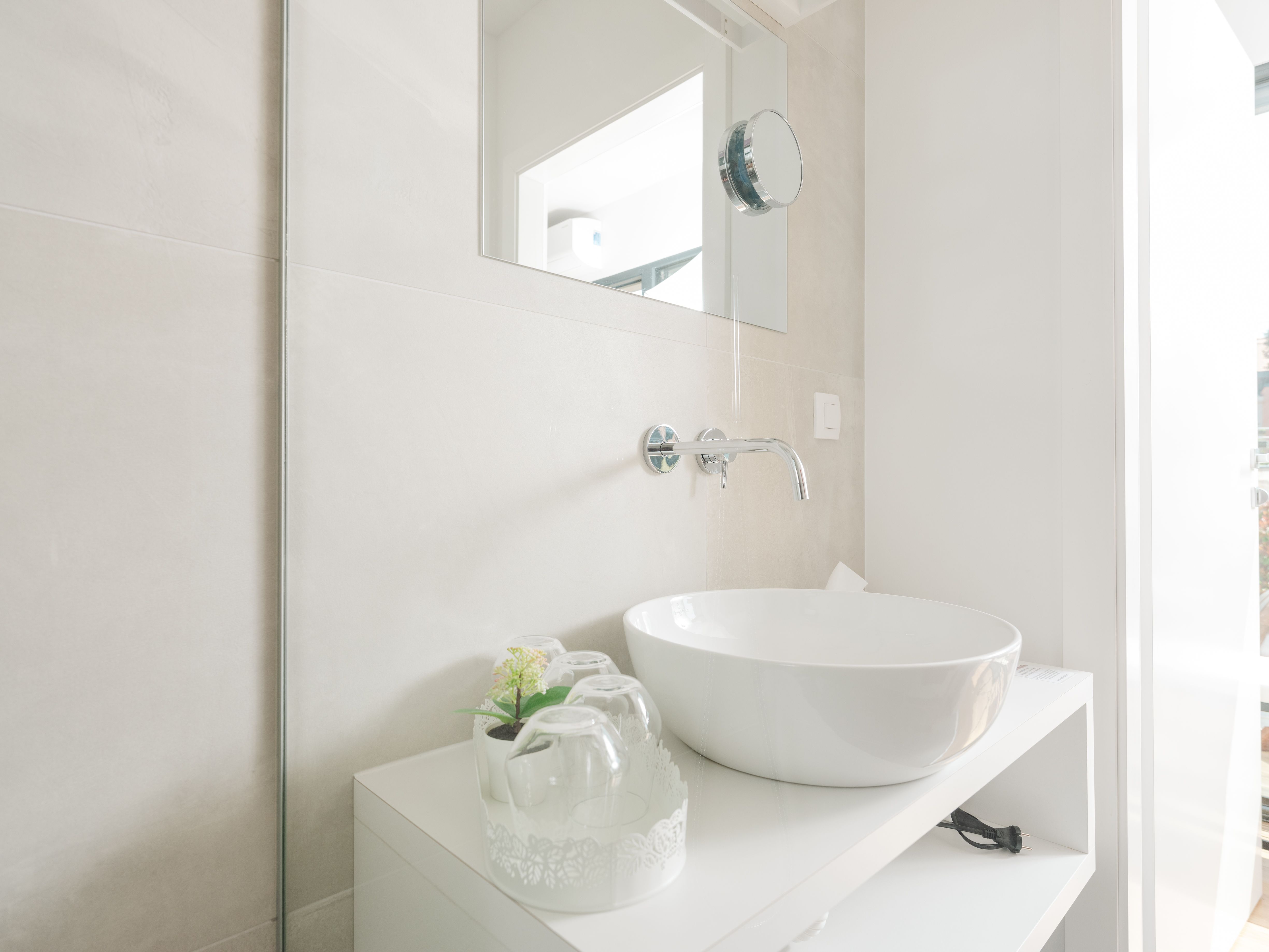 Modernes Badezimmer mit rundem Waschbecken und Spiegel.