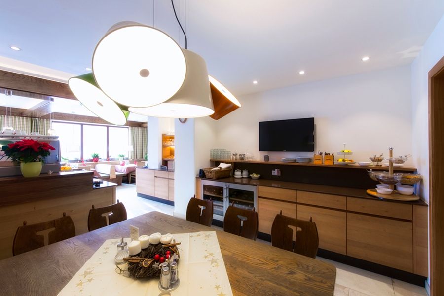 Ein modernes Restaurant mit Holzmöbeln, einem großen Tisch, dekorativen Lampen und einem Fernseher an der Wand.