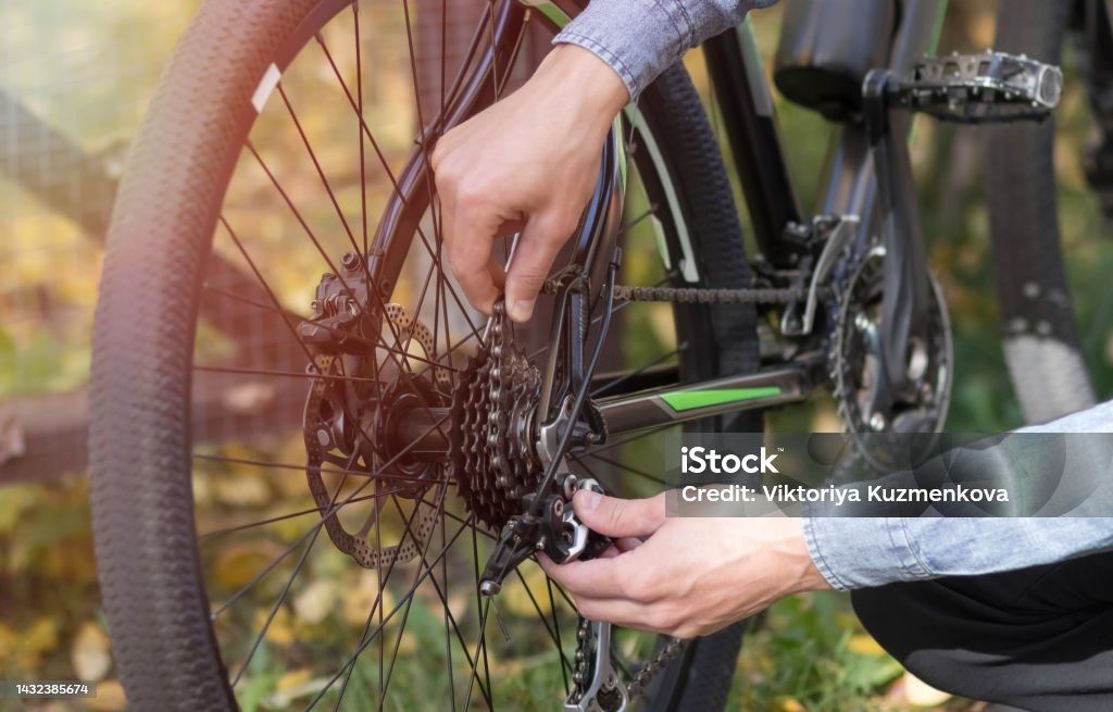 Nahaufnahme von Händen, die an einem Fahrradgetriebe arbeiten.