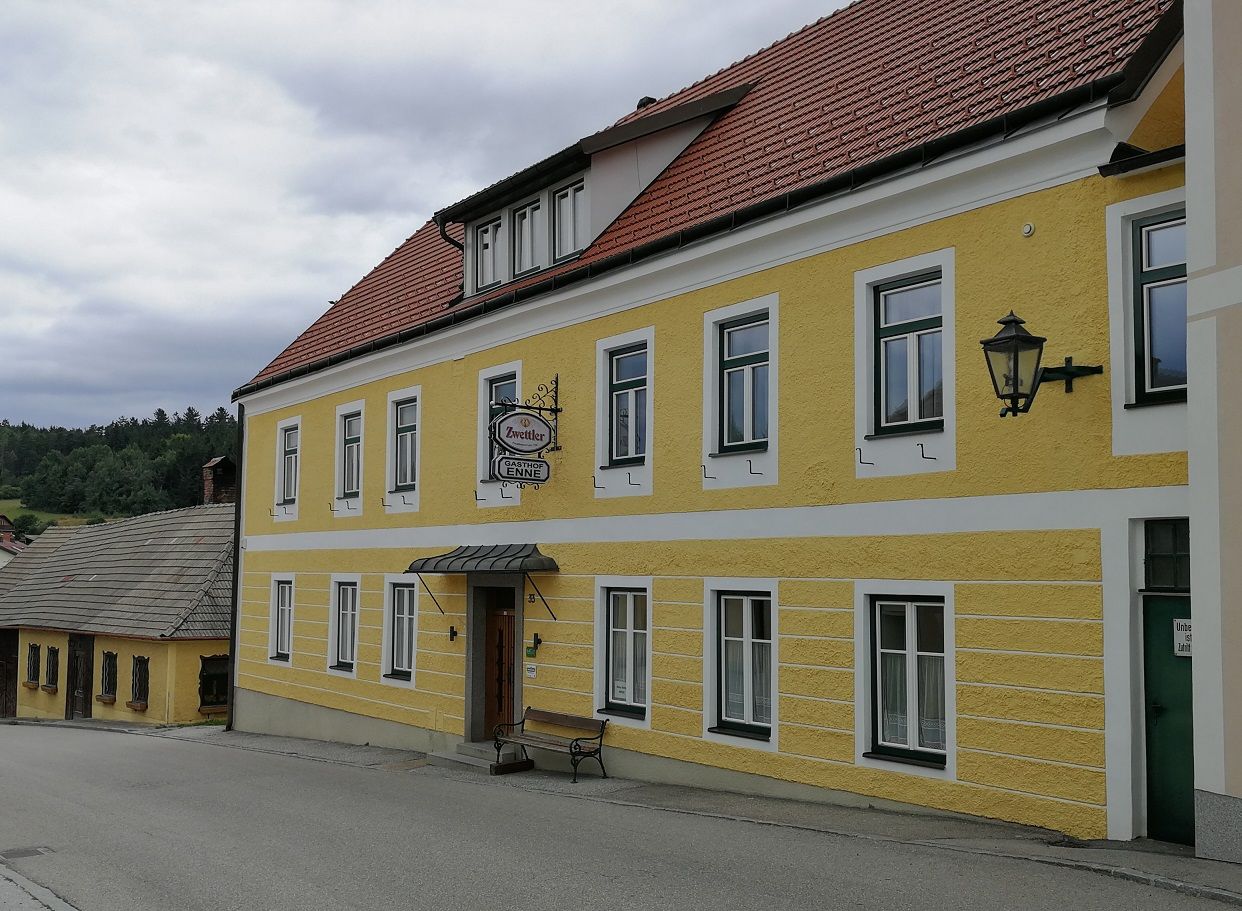 Gelbes Gebäude mit der Aufschrift 'Gasthof Enne' und einem Zwettler-Bierschild.