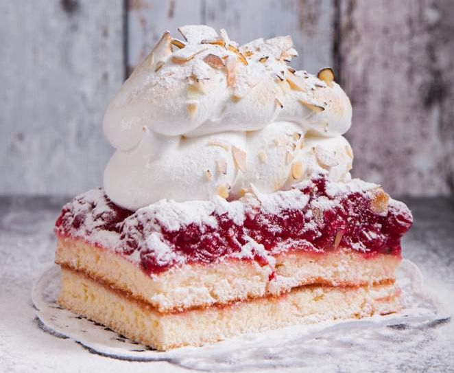 Ein Stück Kuchen mit Sahnehaube und Mandelsplittern.