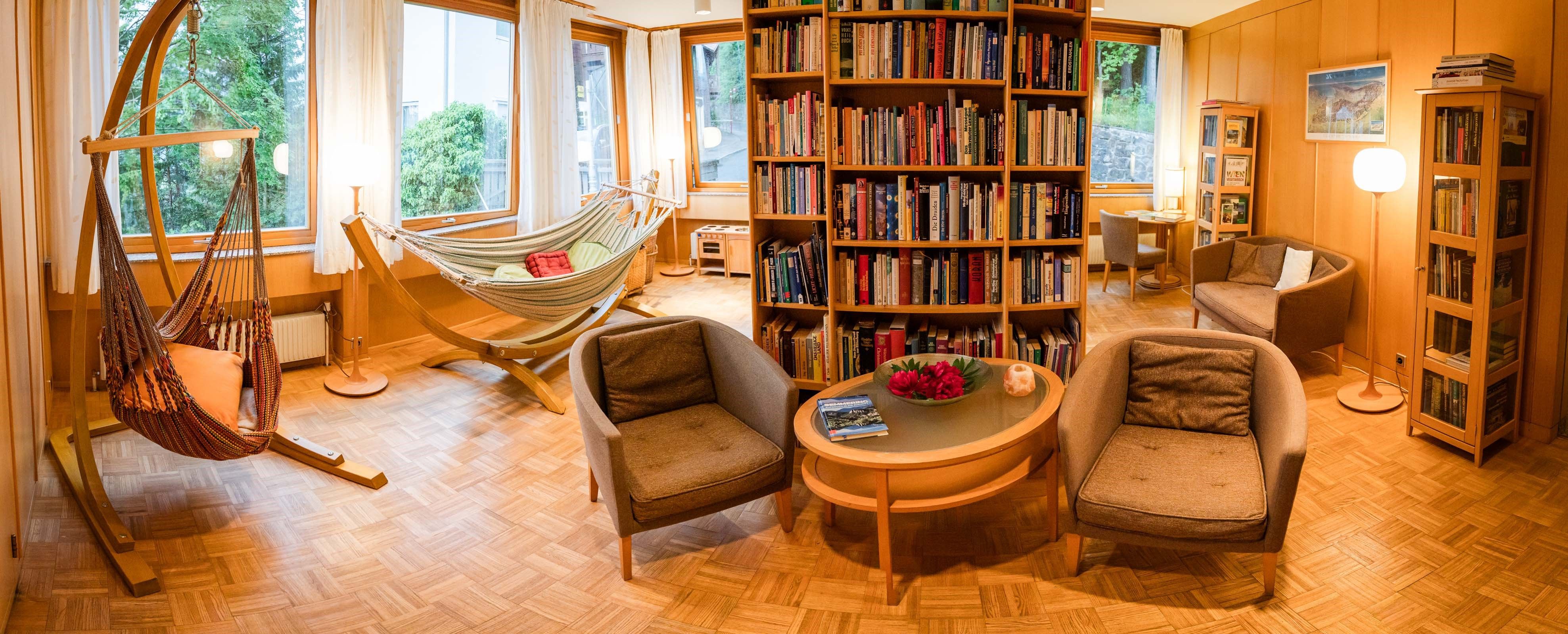 Gemütliche Bibliothek mit Hängematten, Sesseln und Bücherregalen in einem Hotel.