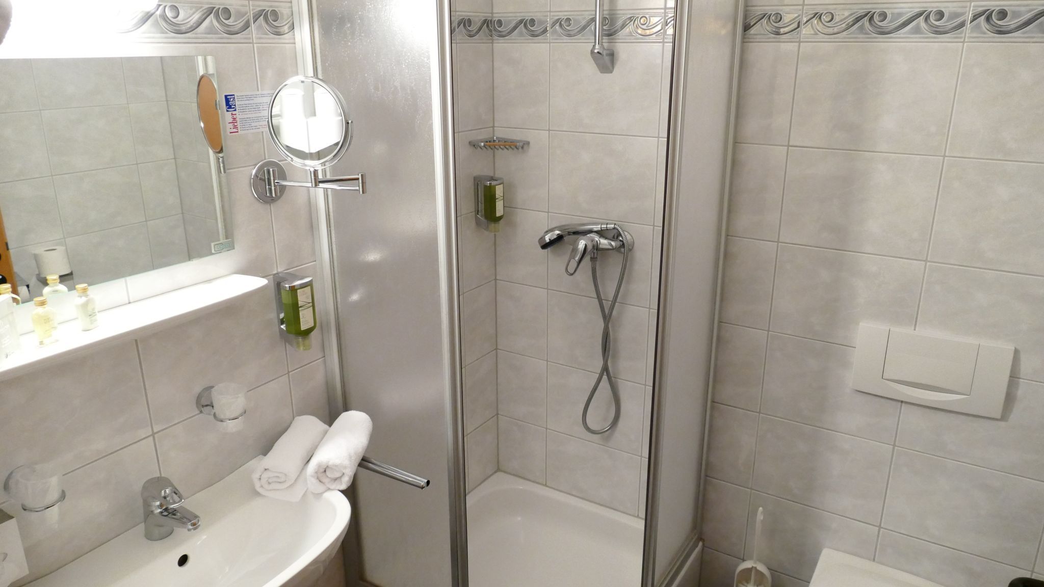 Badezimmer mit Dusche, Waschbecken und Spiegel.