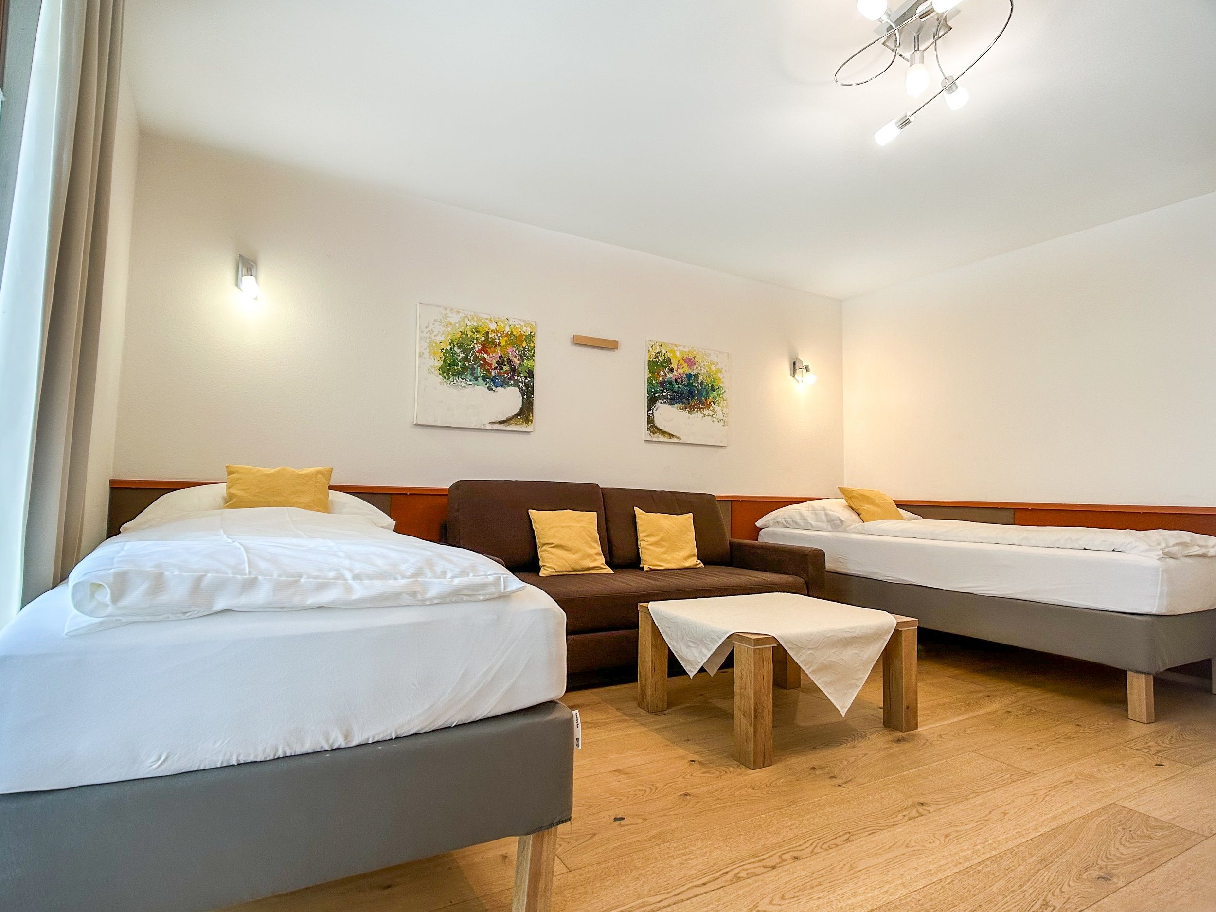 Schlafzimmer mit zwei Betten, Sofa und Tisch.