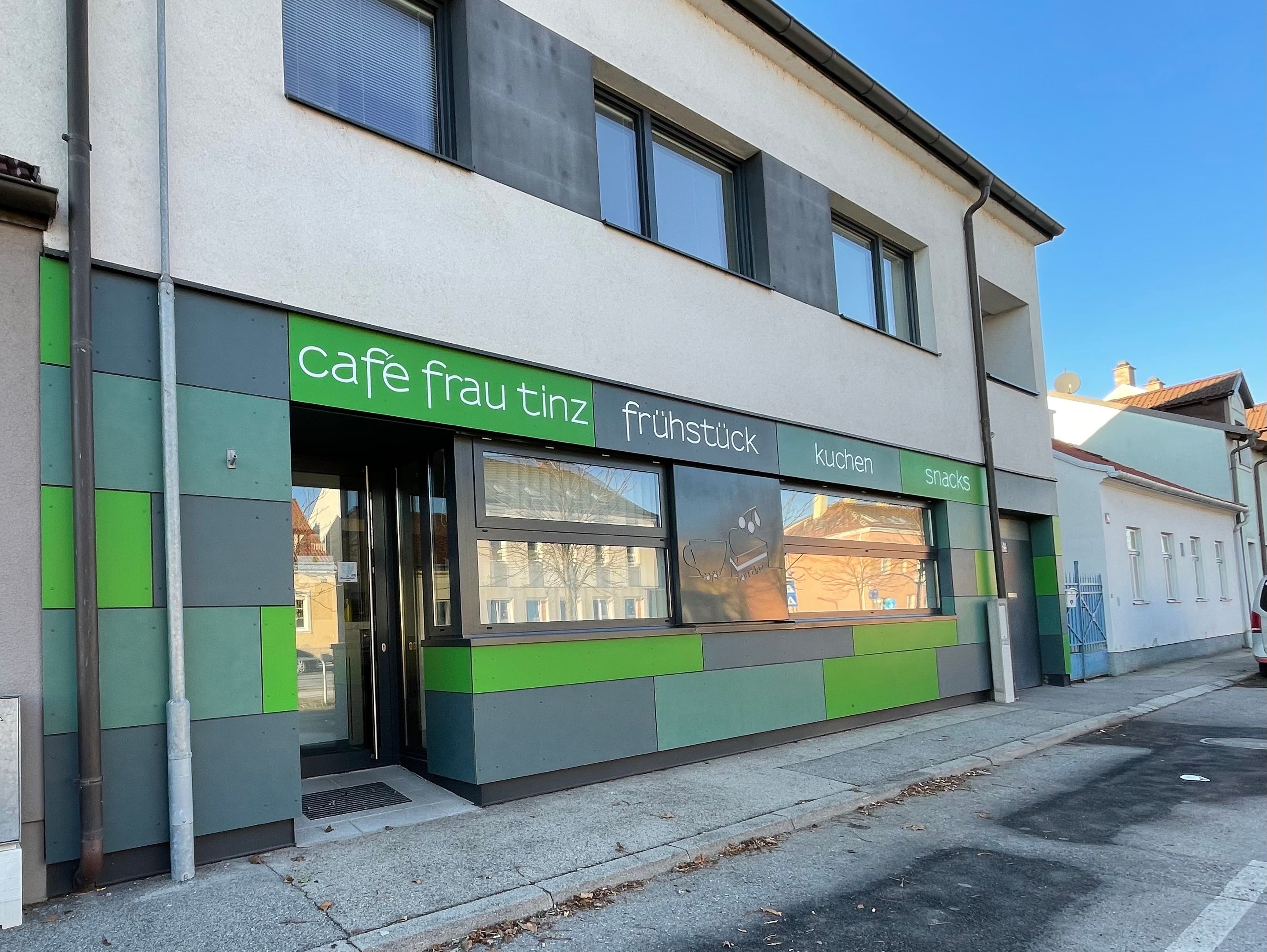 Außenansicht des Cafés Frau Tinz mit grüner und grauer Fassade.