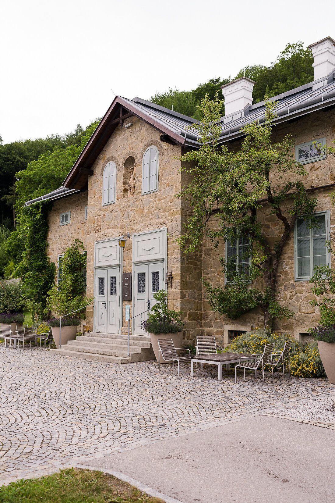 Umgeben von üppigem Grün und sanften Hügeln strahlt das Refugium Hochstrass eine einladende Ruhe aus. Die harmonische Architektur des Hauses fügt sich perfekt in die malerische Landschaft ein und lädt dazu ein, die Seele baumeln zu lassen. Hier erleben Besucher die Schönheit der Natur in vollen Zügen.
