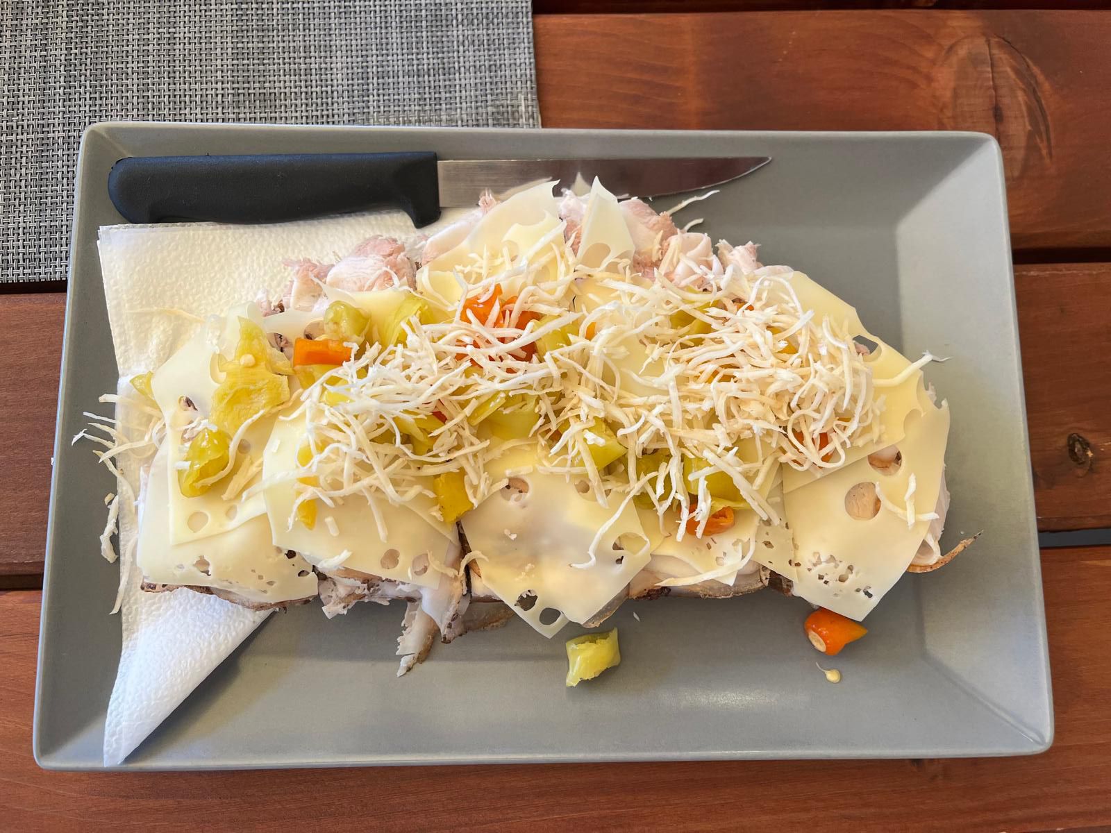 Ein Käsebrot mit Gemüse und geriebenem Kren auf einem grauen Teller.