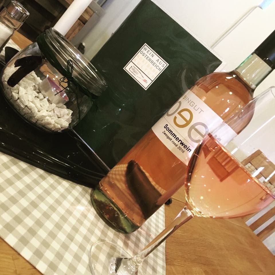 Eine Flasche Roséwein und ein gefülltes Weinglas auf einem Tisch mit Dekoration.