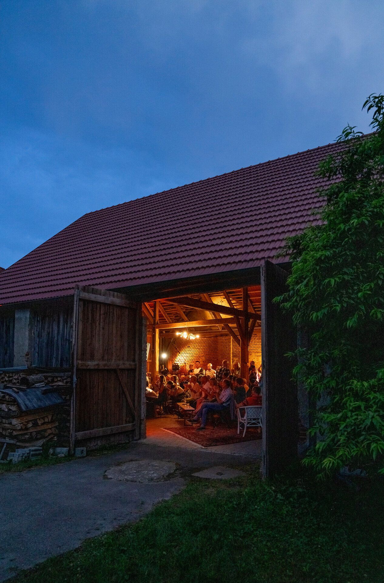 In der warmen Abenddämmerung versammeln sich Menschen in einem einladenden Hof, um die köstlichen Weine der Region zu genießen. Die sanfte Beleuchtung und die rustikale Atmosphäre schaffen eine perfekte Kulisse für gesellige Gespräche und unvergessliche Momente.