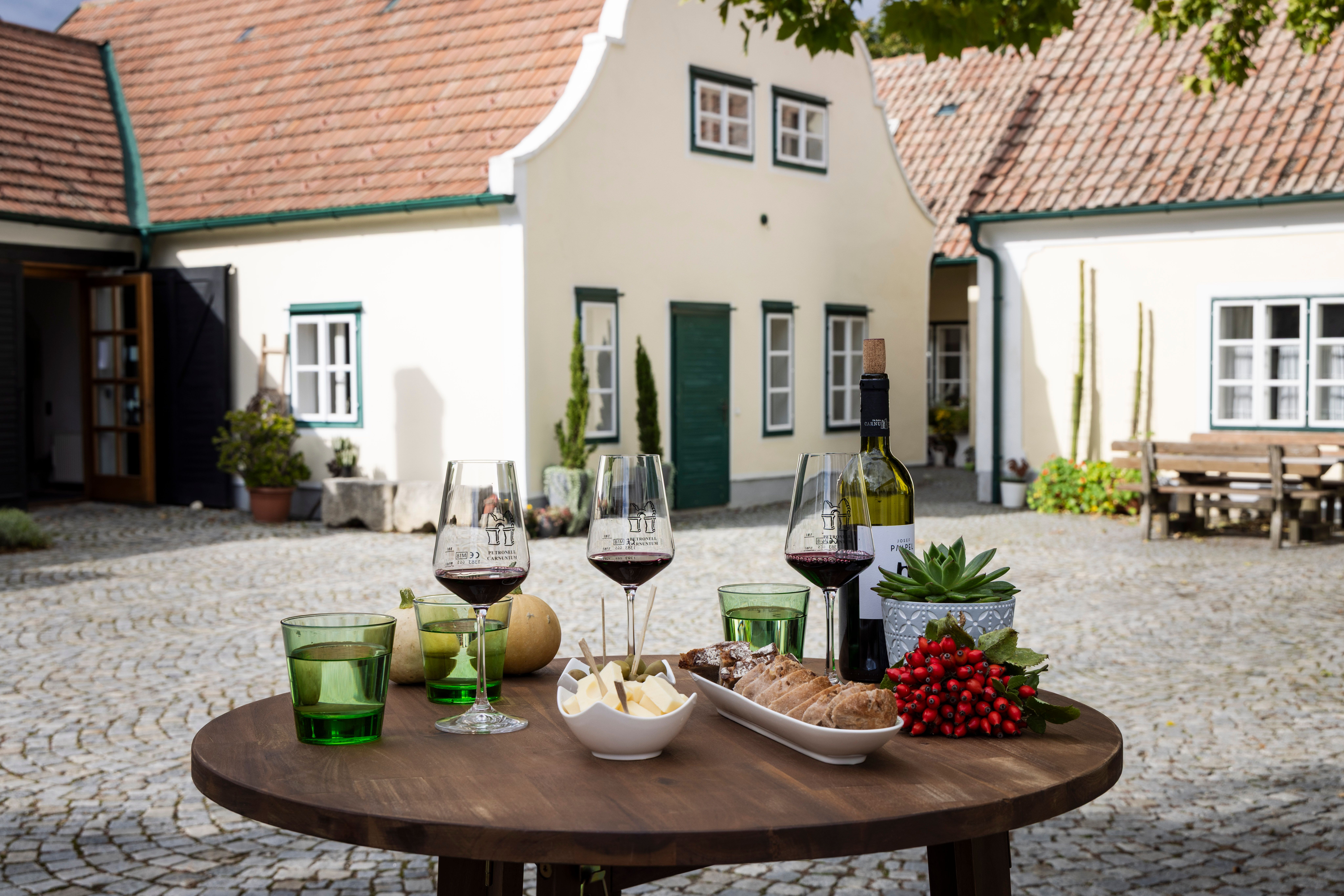 Tisch mit Weingläsern, Käse und Brot am Weingut im Innenhof