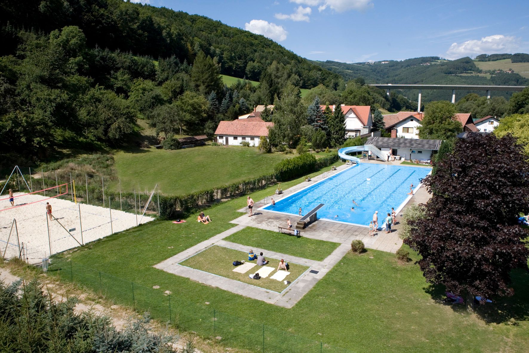 Freibad Edlitz mit Schwimmbecken, Rutsche und Volleyballfeld in ländlicher Umgebung.