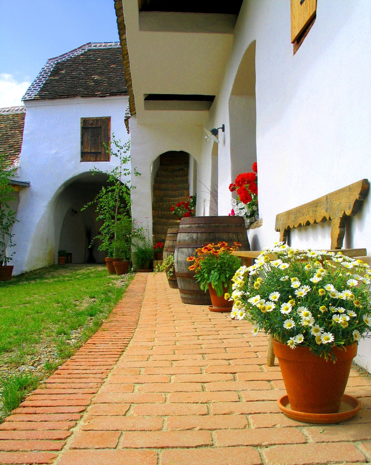 Traditioneller Innenhof mit Blumen und Holzfässern.