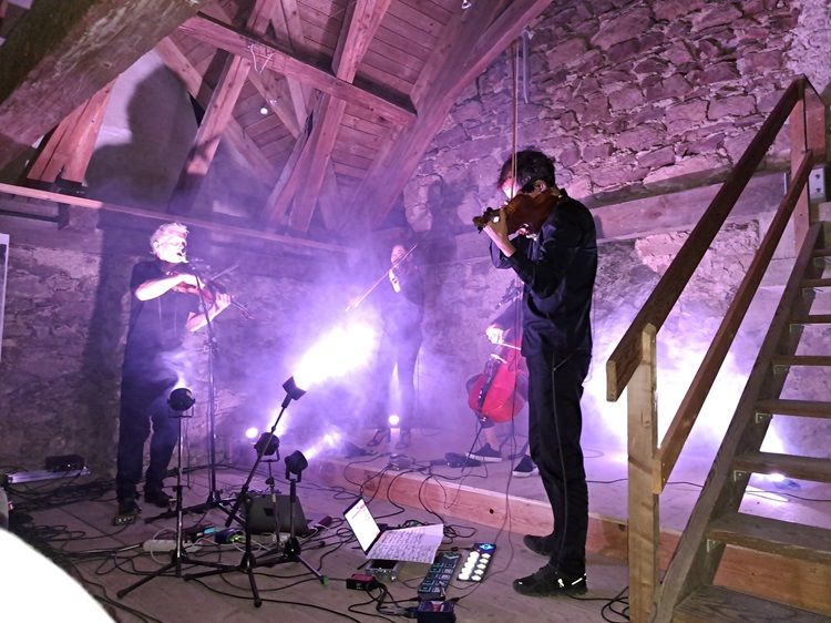 Musiker spielen in einem rustikalen Dachboden mit Lichteffekten.