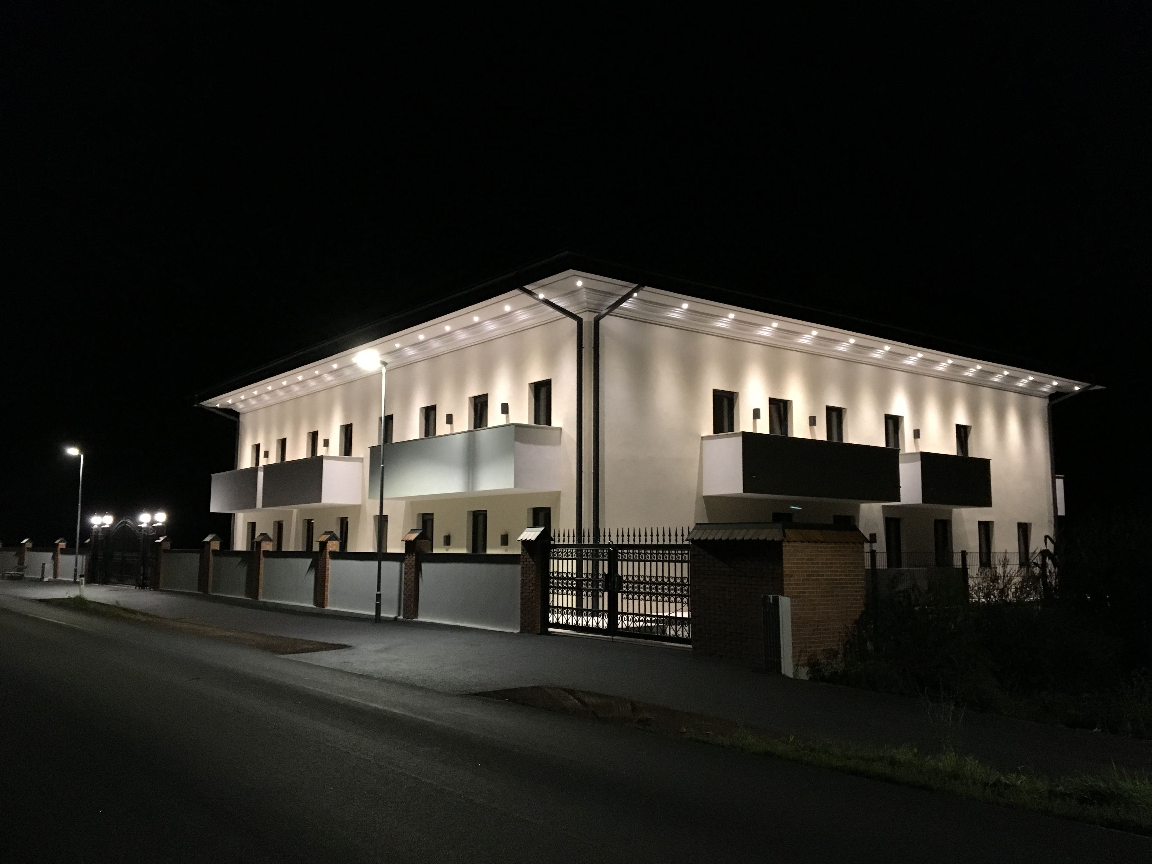 Beleuchtetes Gebäude bei Nacht mit Balkonen und Straßenlaternen.