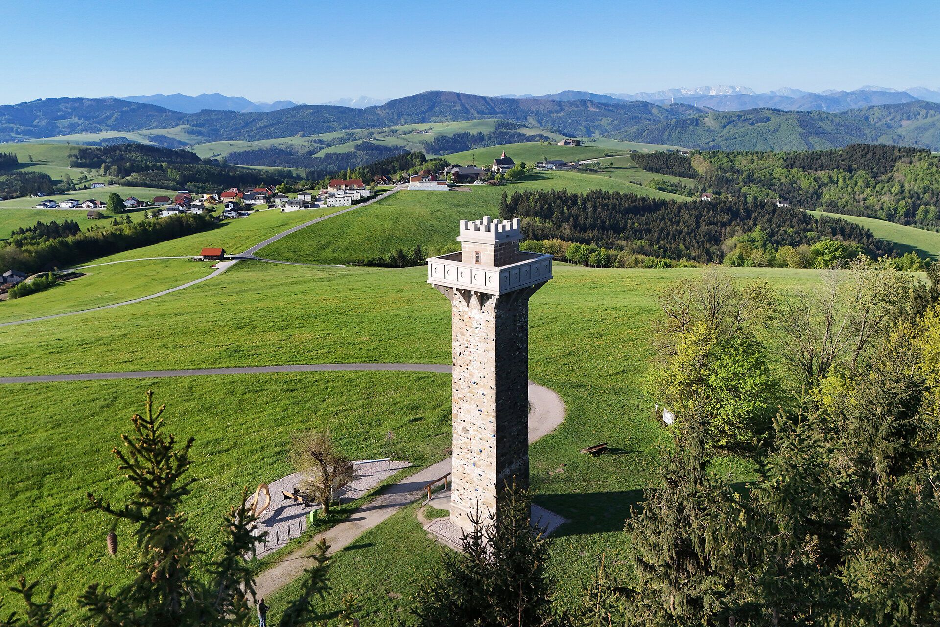 Aussichtsturm inmitten grüner Hügellandschaft.