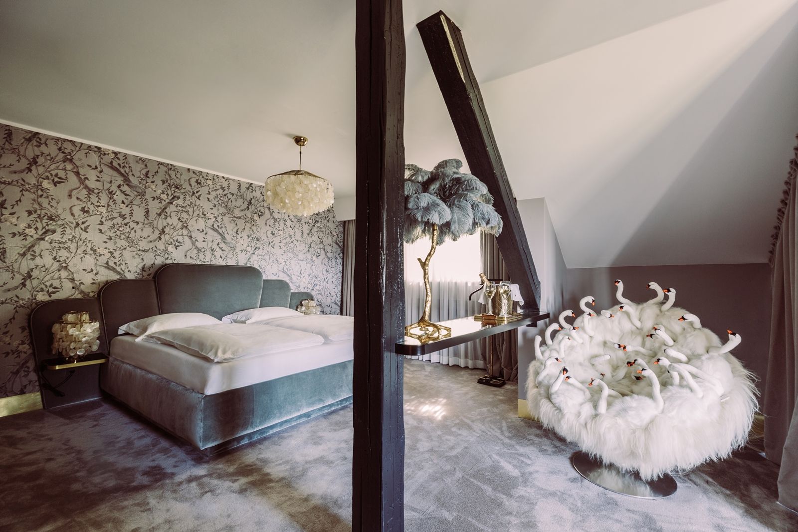 Luxuriöses Schlafzimmer mit großem Bett, dekorativer Tapete, Kronleuchter und extravagantem Sessel mit Schwanendesign.