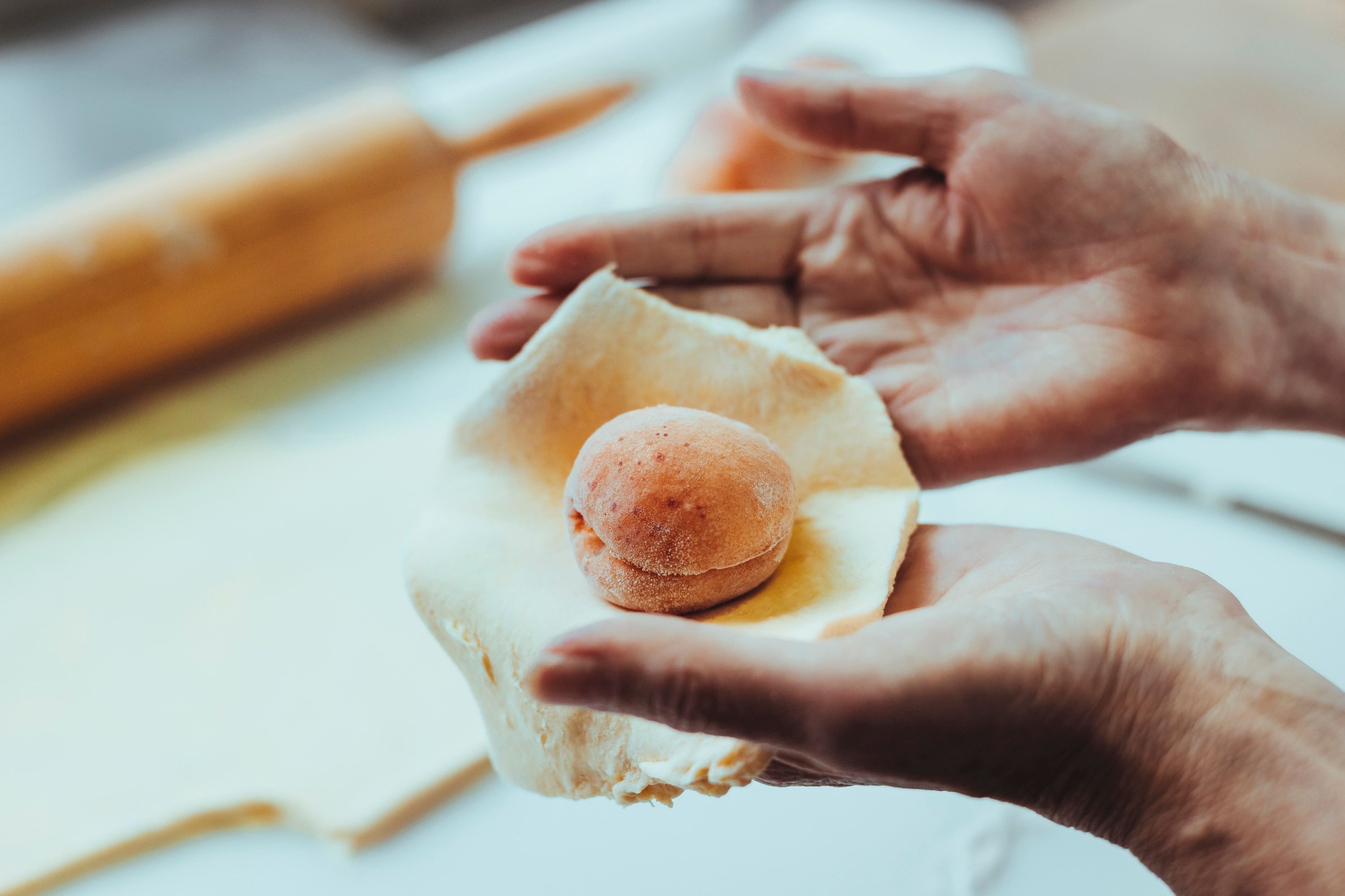 Hände formen einen Teig um eine Marille.
