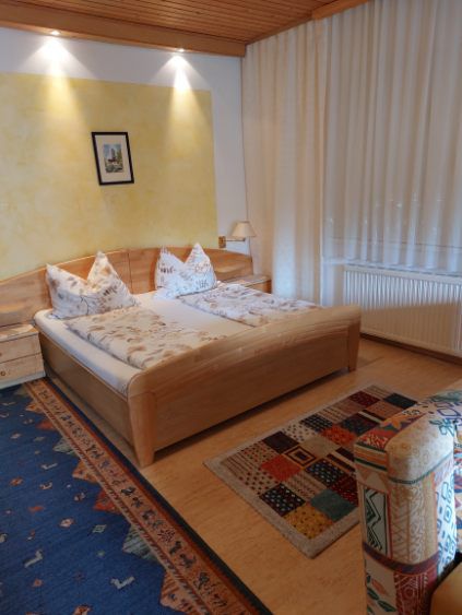 Gemütliches Gästezimmer mit Doppelbett, bunten Teppichen und Holzmöbeln.