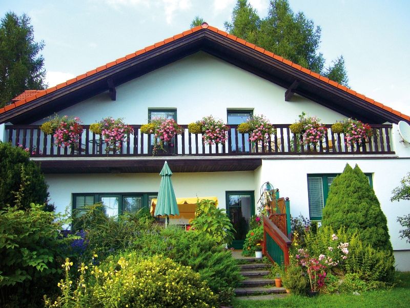 Ein zweistöckiges Haus mit Balkon und Blumen.